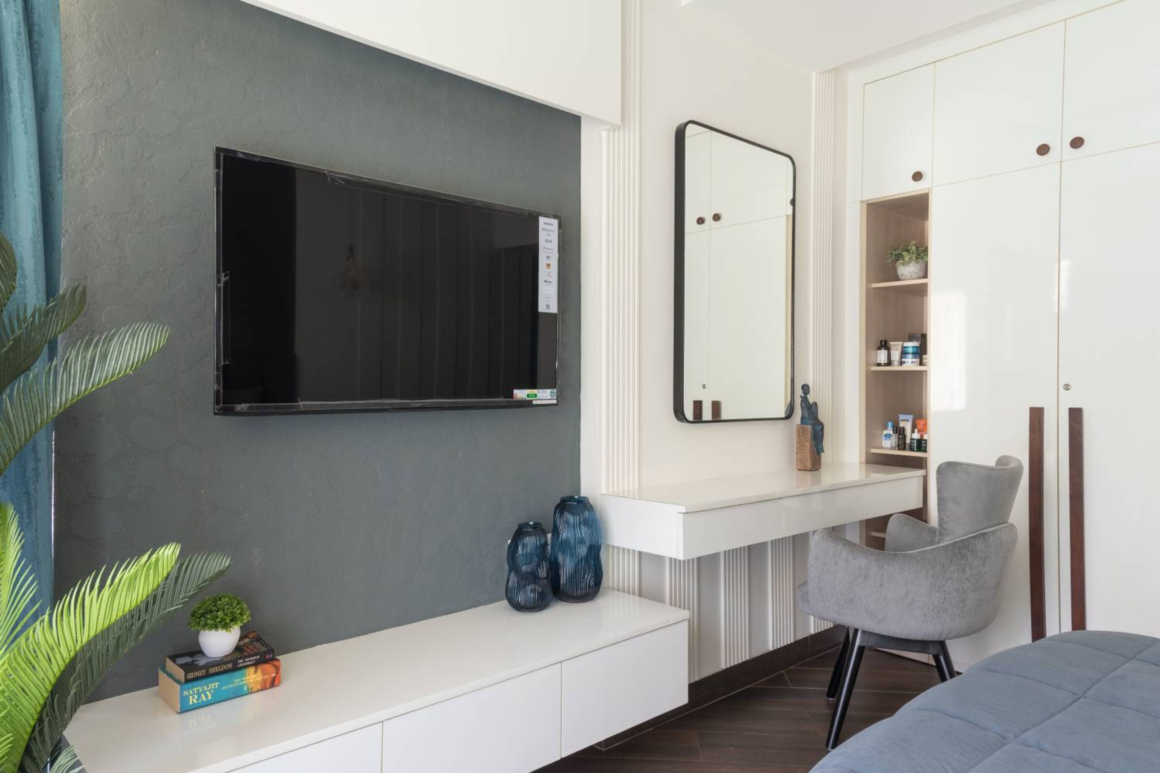Bedroom Design with TV Unit and Vnaity with Grey Chair and Wall Mounted Mirror