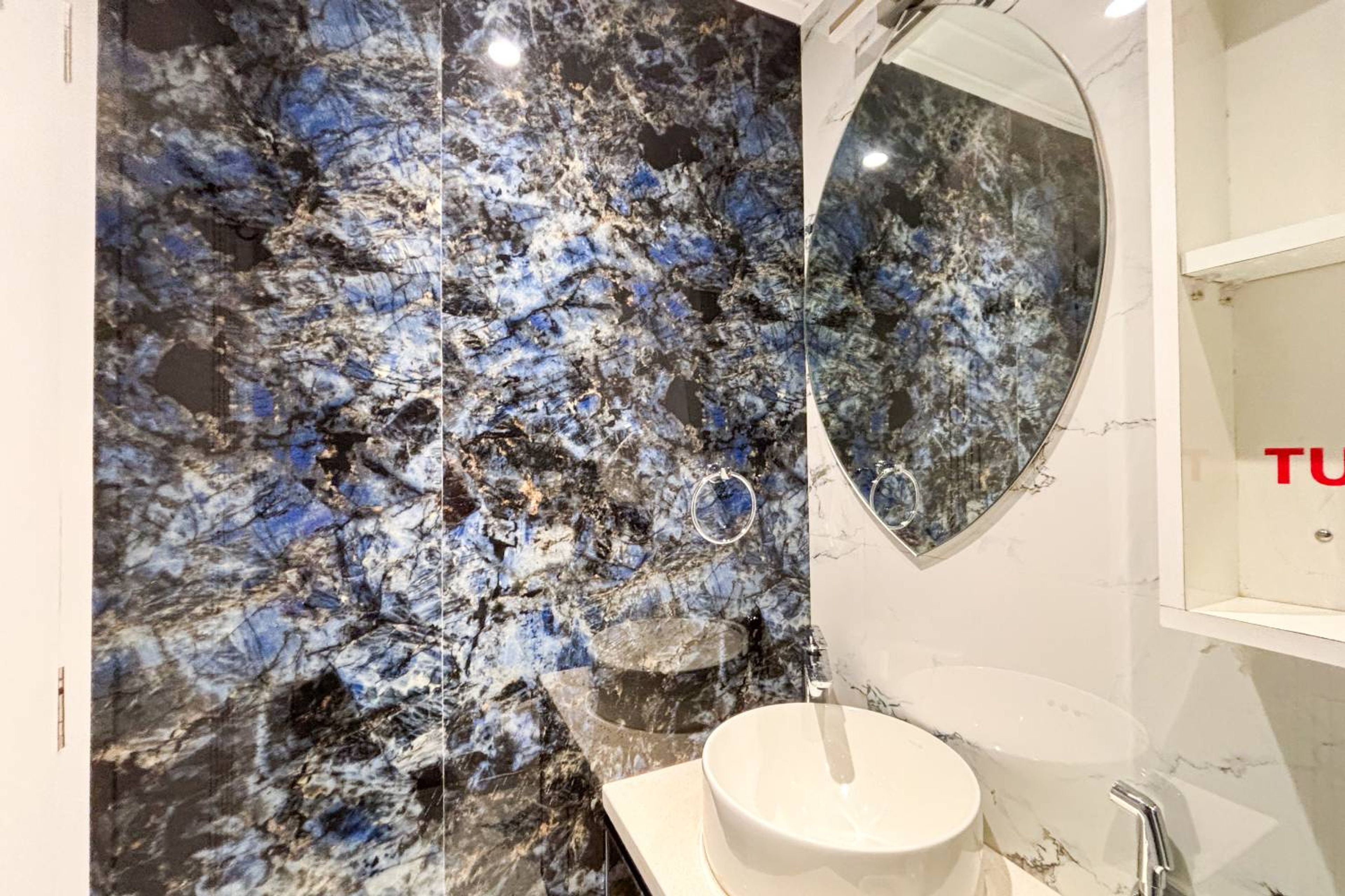 Bathroom design with textured black and blue wall and oval mirror