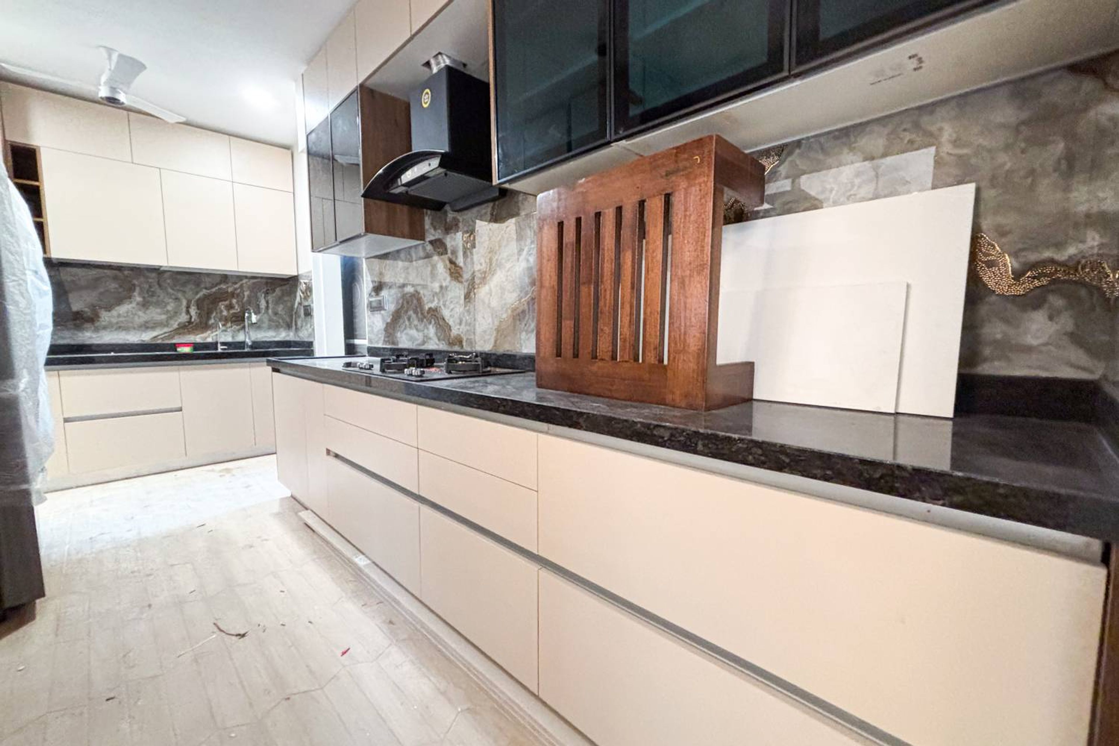 Modular Parallel Kitchen Design with Beige Base Cabinets, Black Countertop, and Glossy Brown Marble Backsplash
