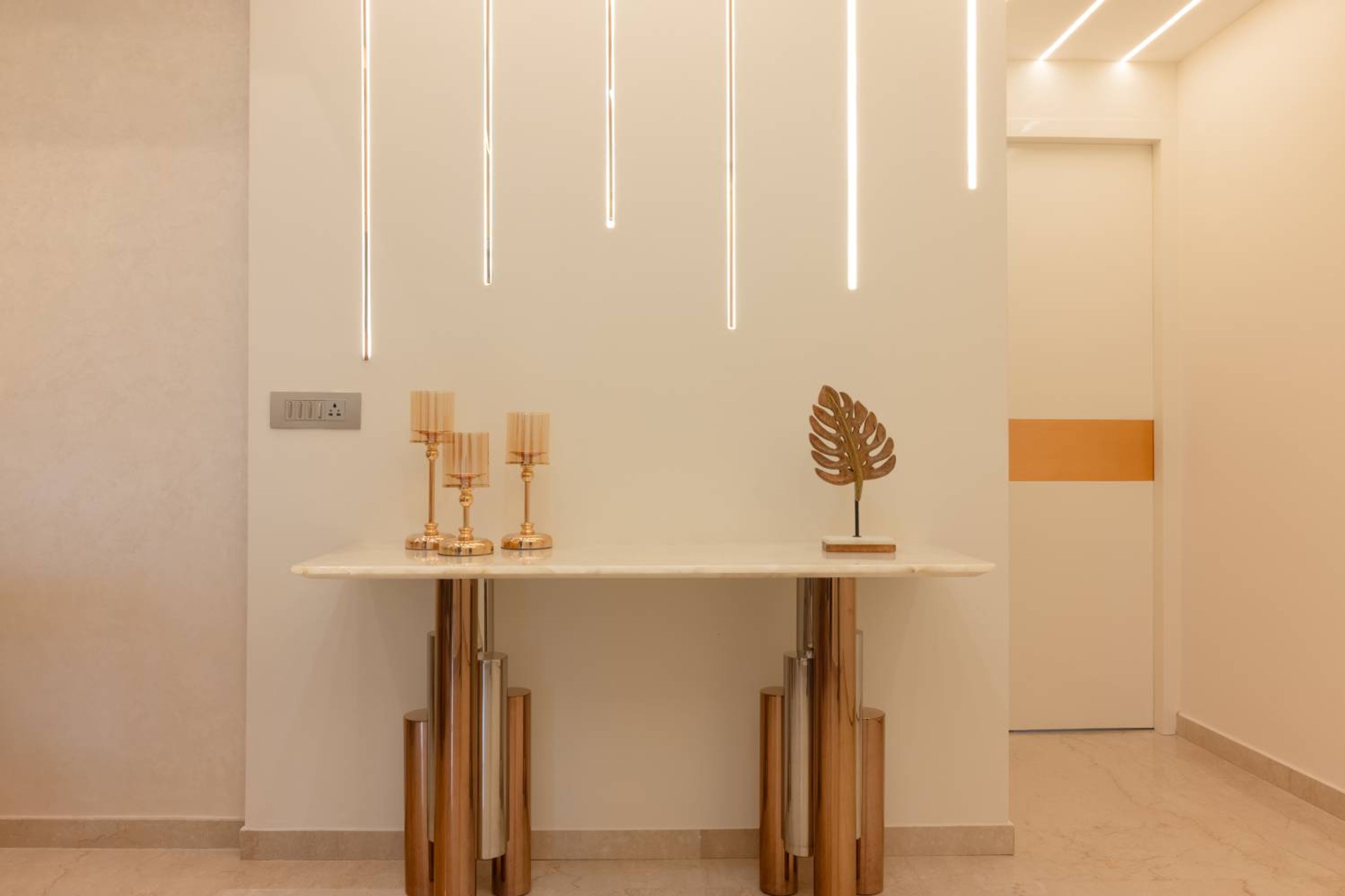 Entryway Design with Vertical Linear Wall Lights and Marble-Top Console Table with Gold Accents