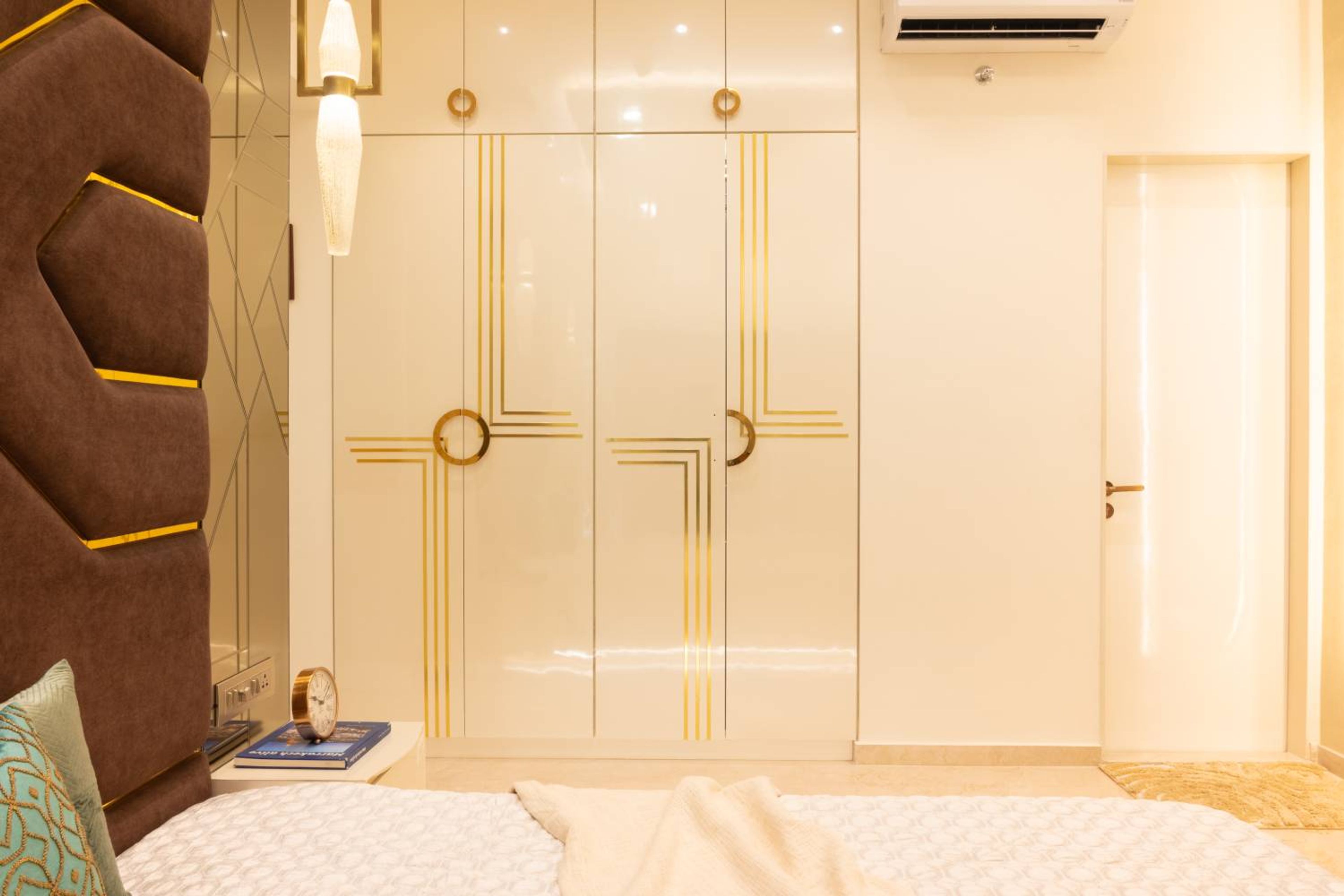 Bedroom Design with White Gloss Swing Wardrobes, Gold Accent Handles, and Geometric Padded Headboard Wall