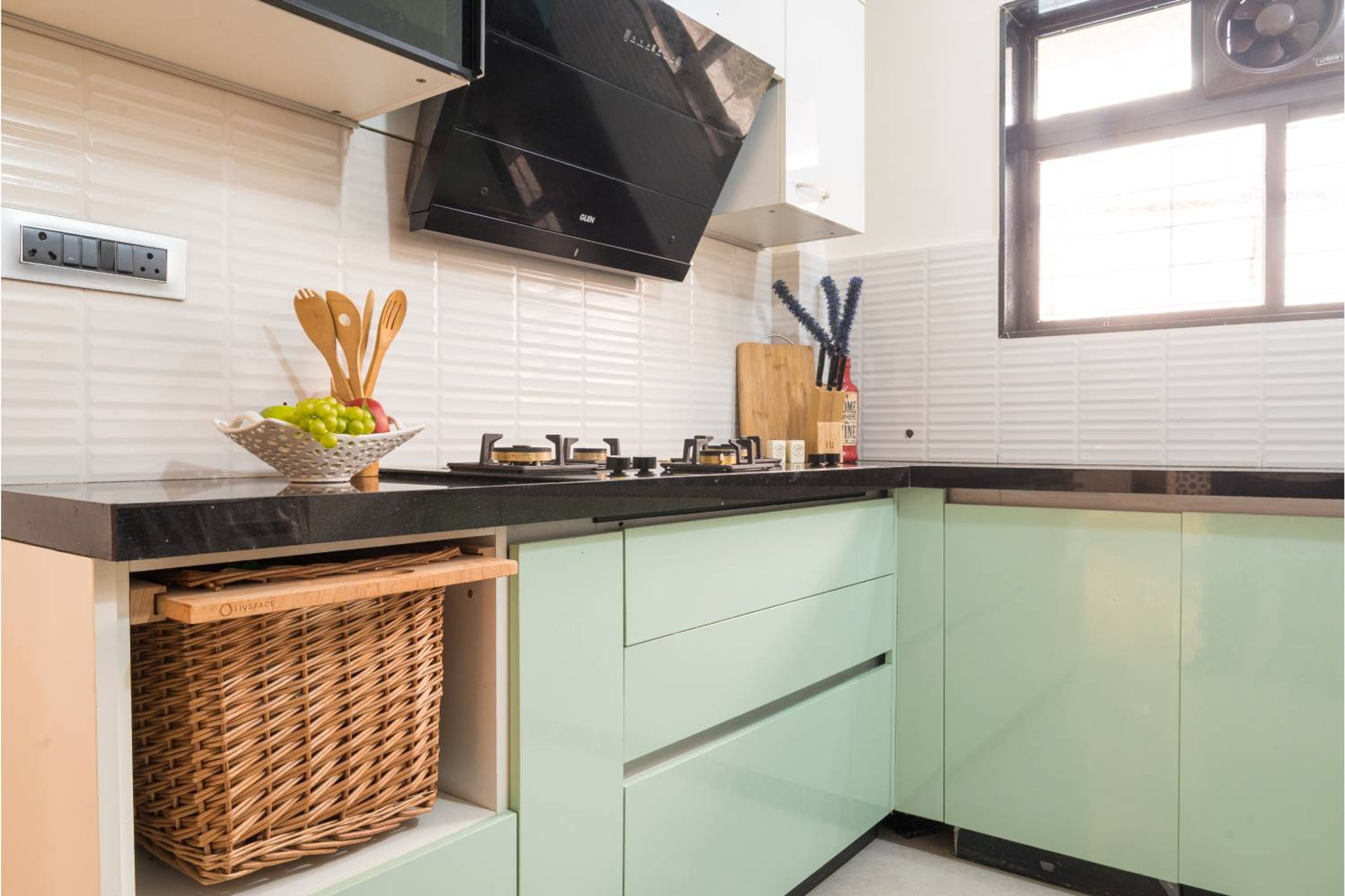 Modern L-Shaped Kitchen Design with Sage Green and White Cabinets and Black Countertops