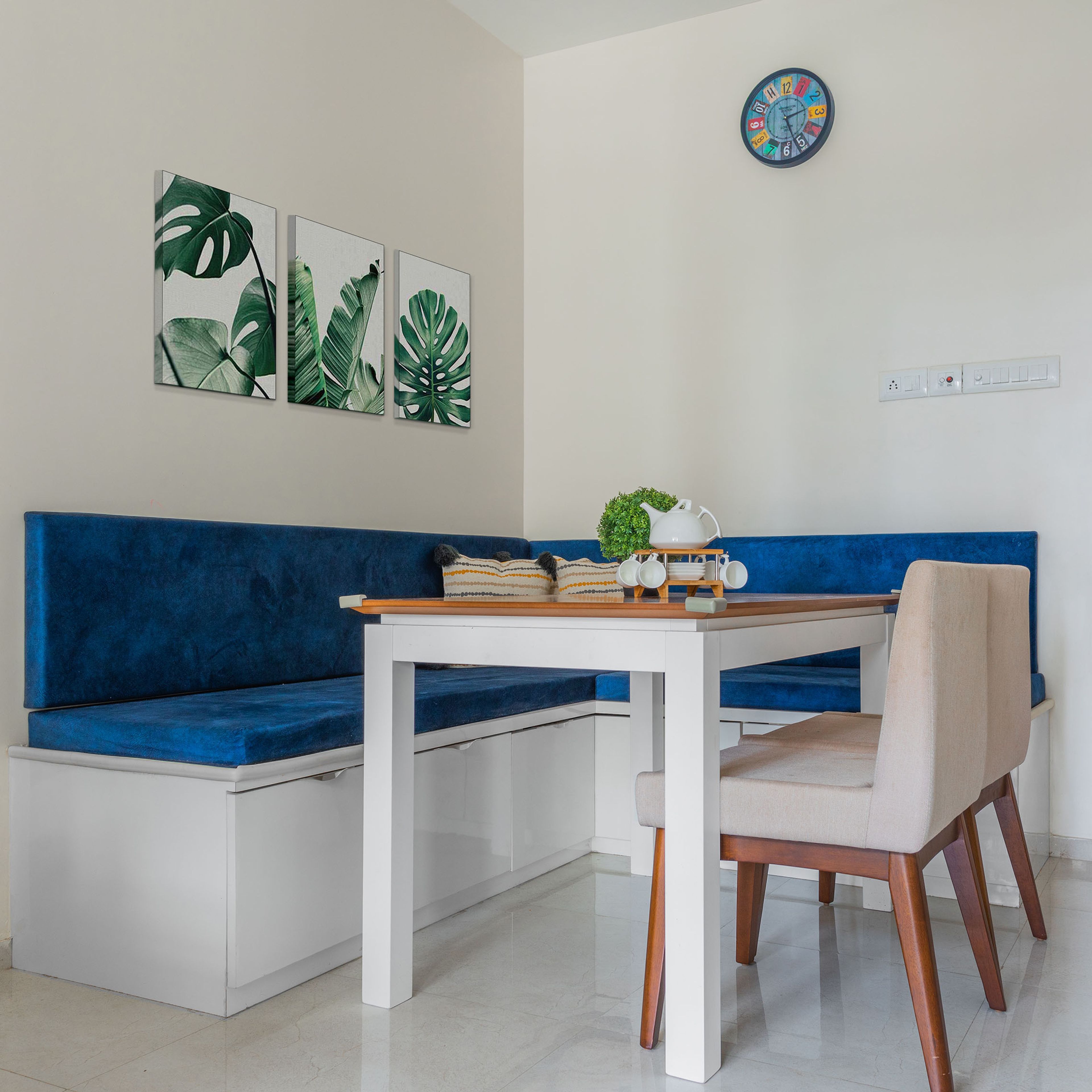 Dining Room Design with Wooden Table Top, 2 Beige Chairs, and Blue Cushioned L-Shaped bench Seating