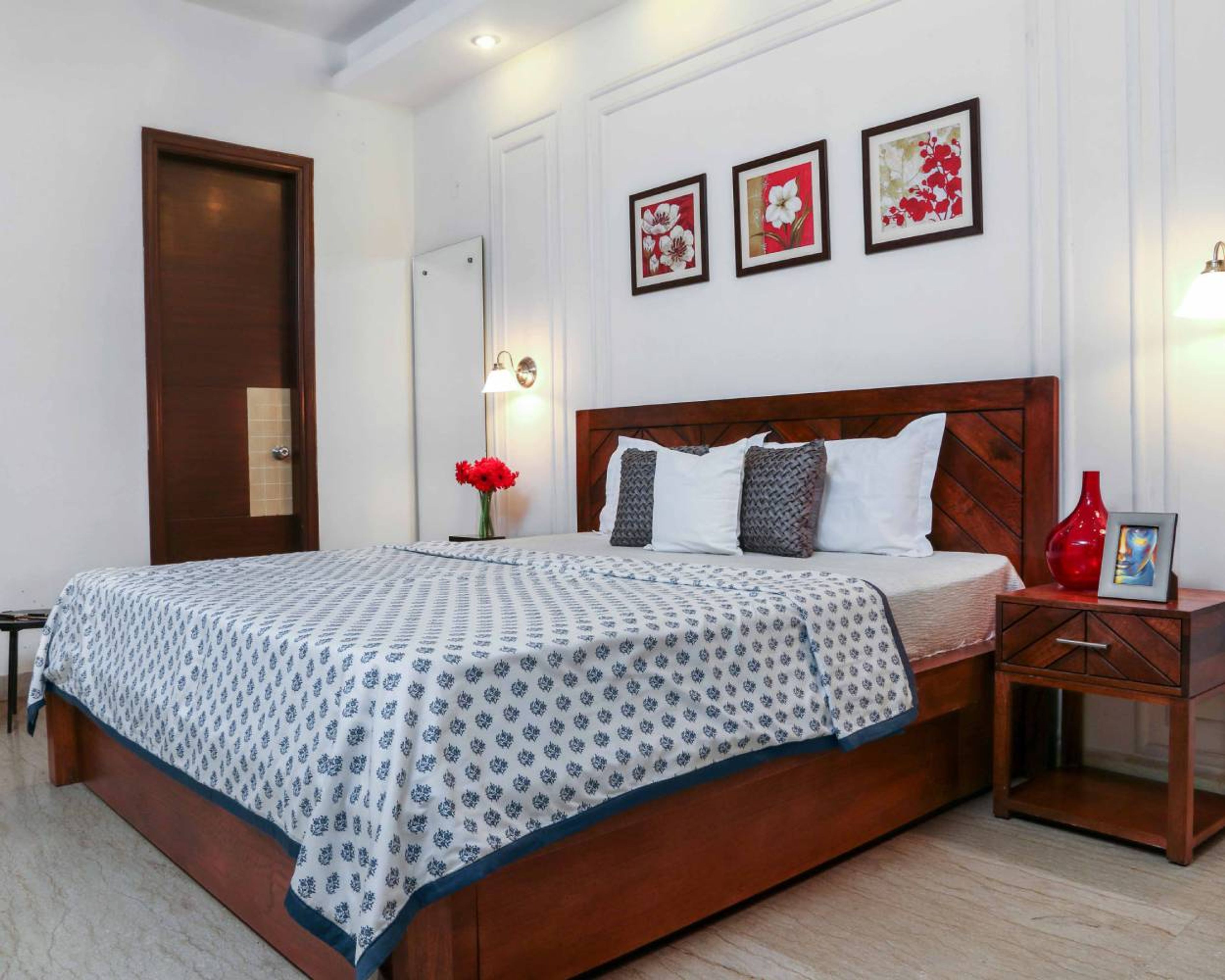 Guest Bedroom Design with White Wall with Trims, Wooden Side Table, and Wall-Mounted Mirror
