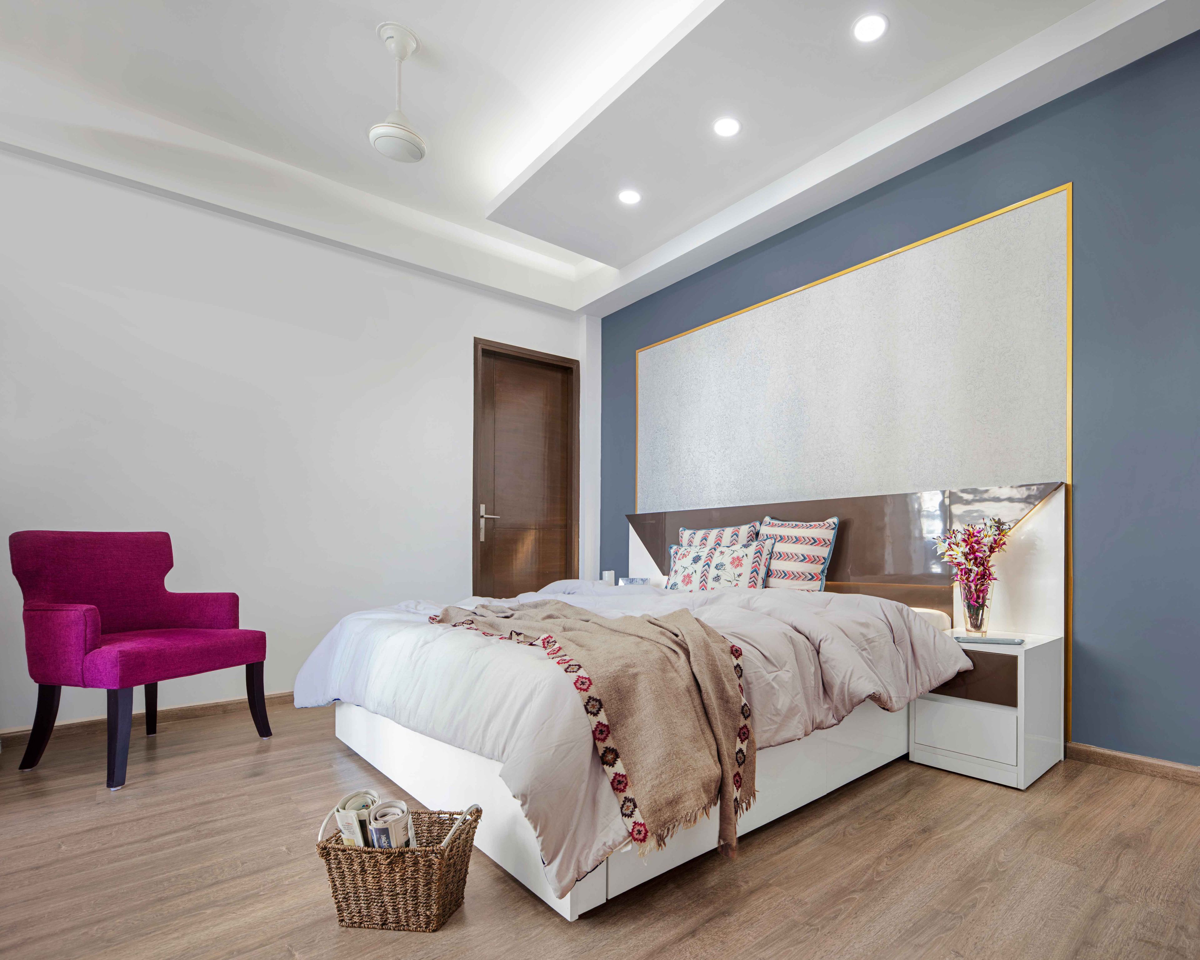 Guest Bedroom Design with Blue and White Wall with Golden Trims, Plum Accent Chair and Wooden Flooring