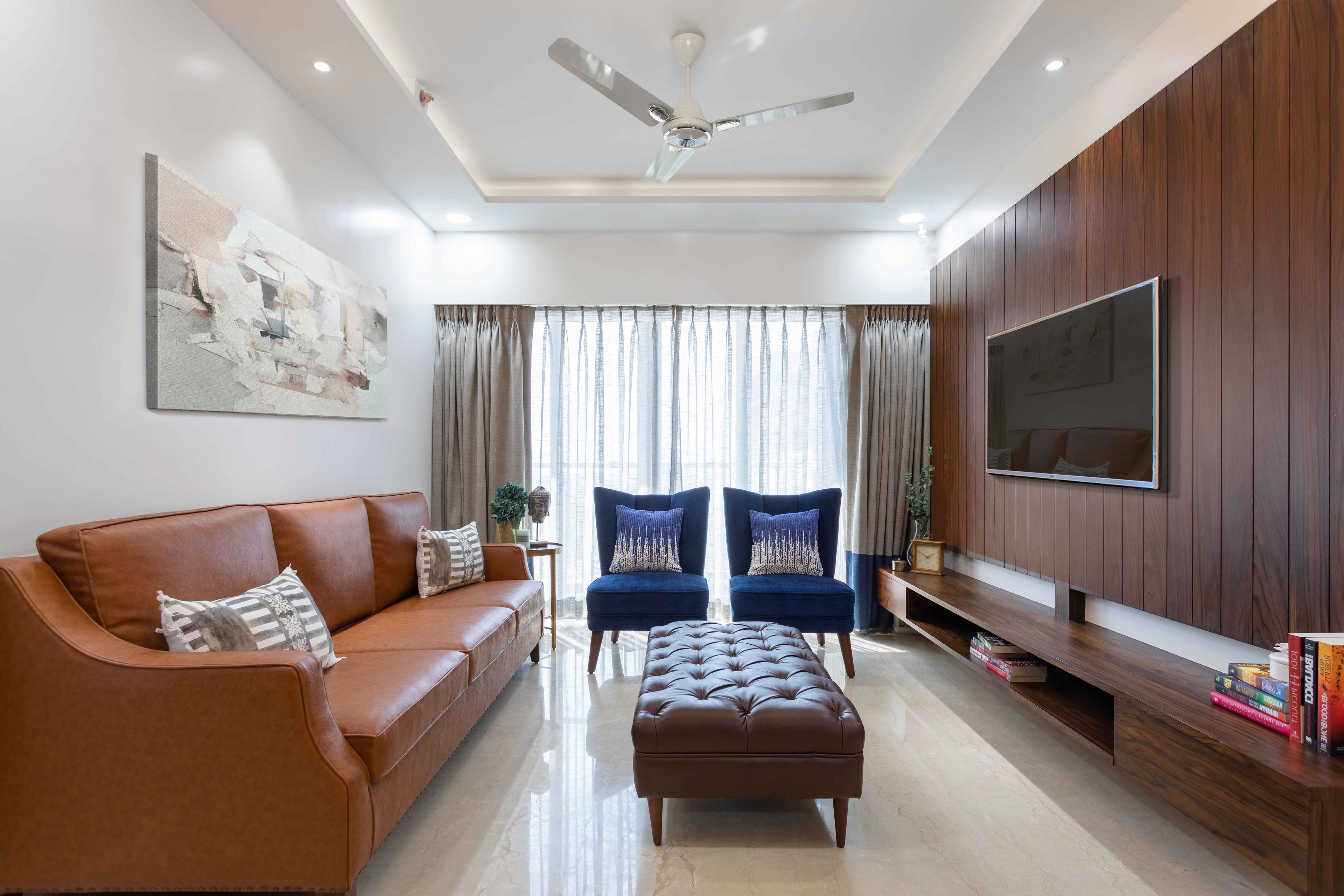 Living Room Design with Orange Leather Sofa, 2 Blue Accent Chairs, Cushioned Dark Brown Leather Table, and Wooden TV Unit