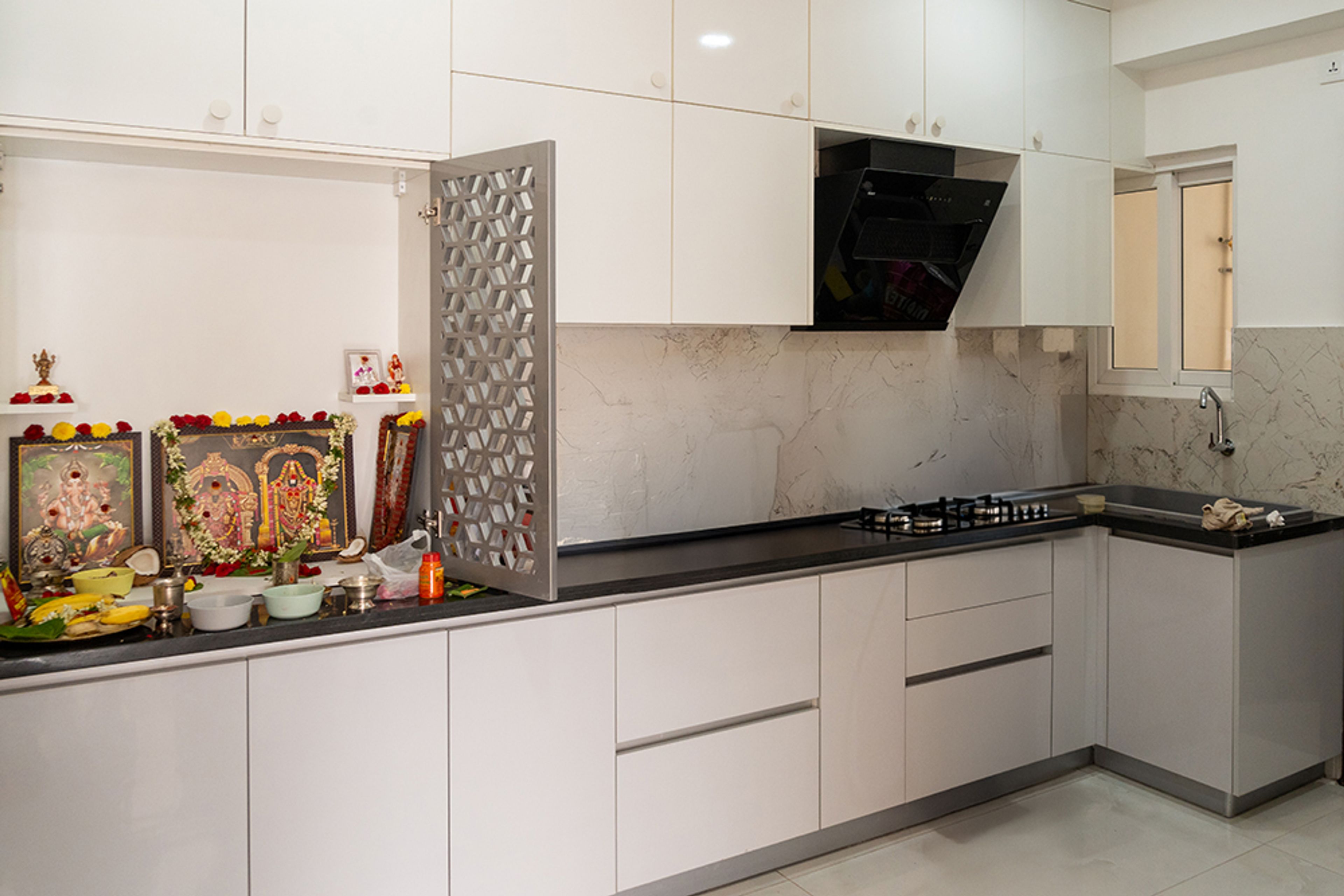L-Shaped Kitchen Design With Pooja Unit and Marble Backsplash