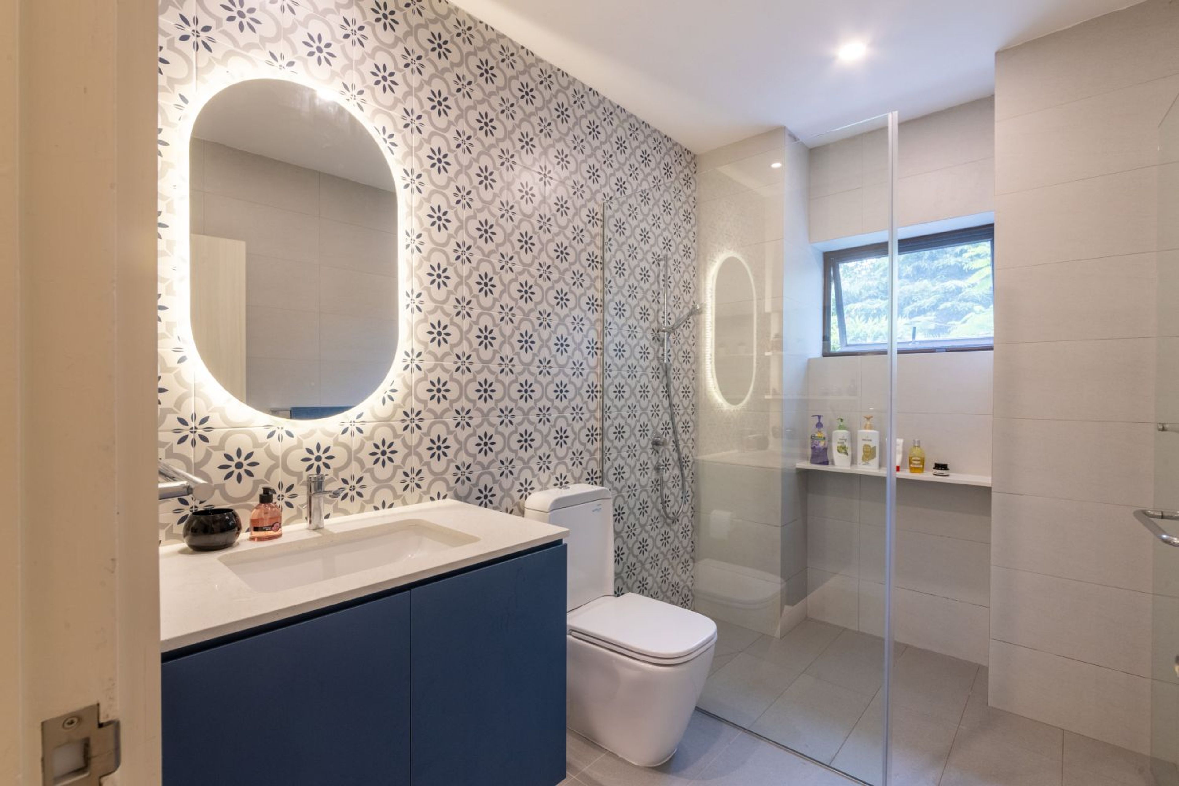 Modern bathroom with white, grey, and blue tiles and wall-mounted blue vanity unit -Livspace