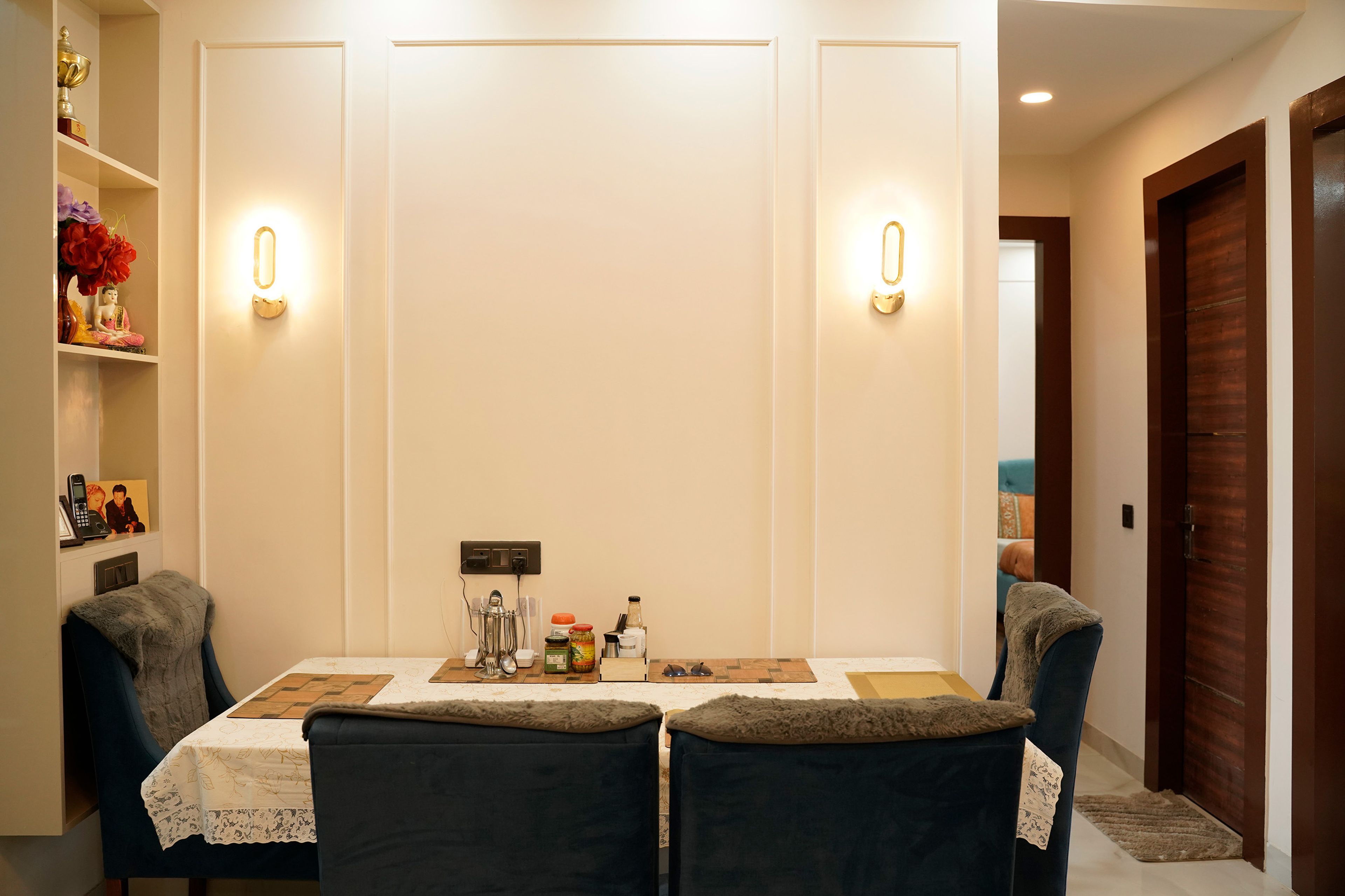 Dining area with cozy chairs, wall sconces, and open shelving for decor display