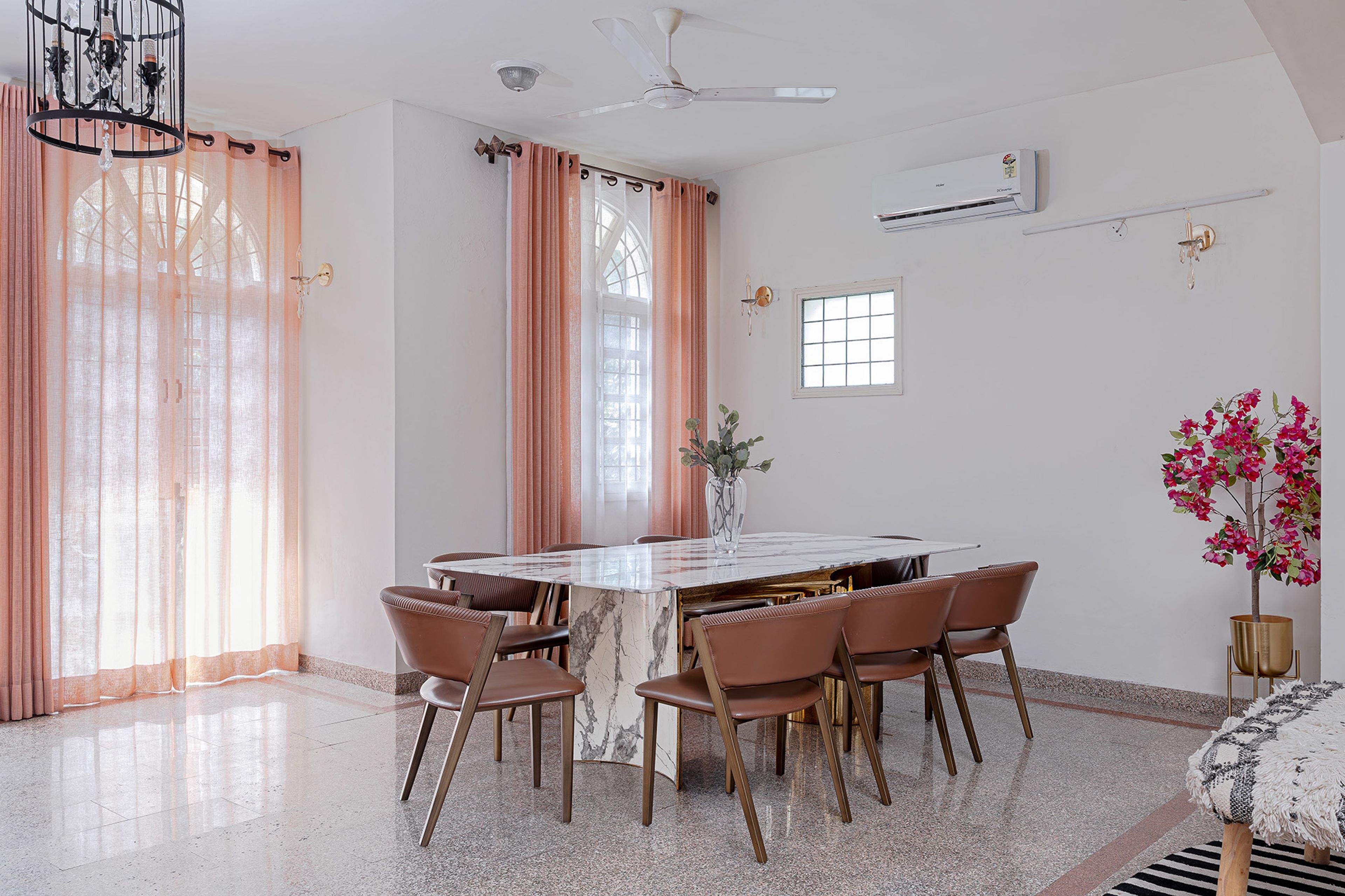 Dining area with marble table, blush curtains, and natural light creating a warm ambiance