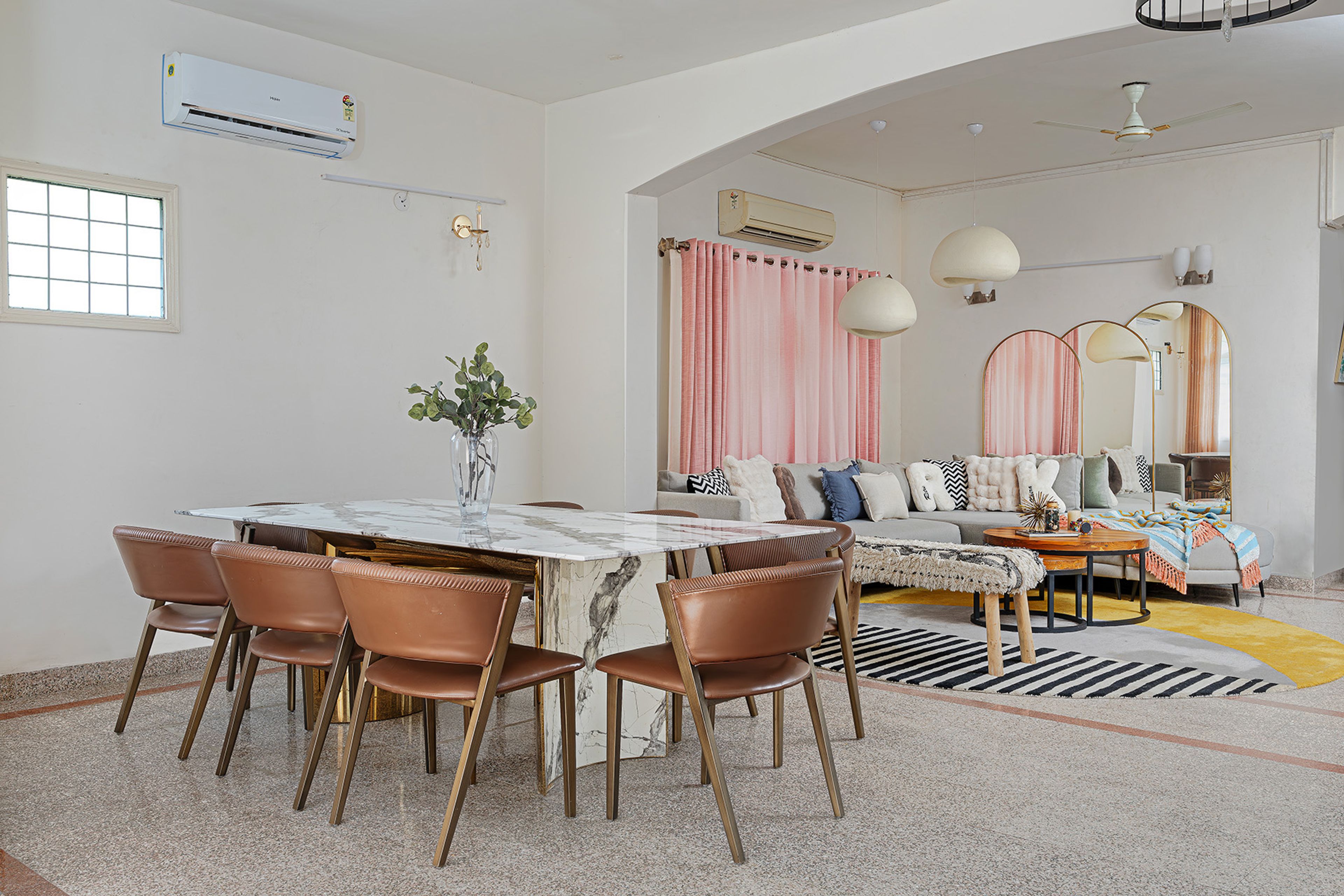 Dining area with marble table, blush curtains, and natural light creating a warm ambiance
