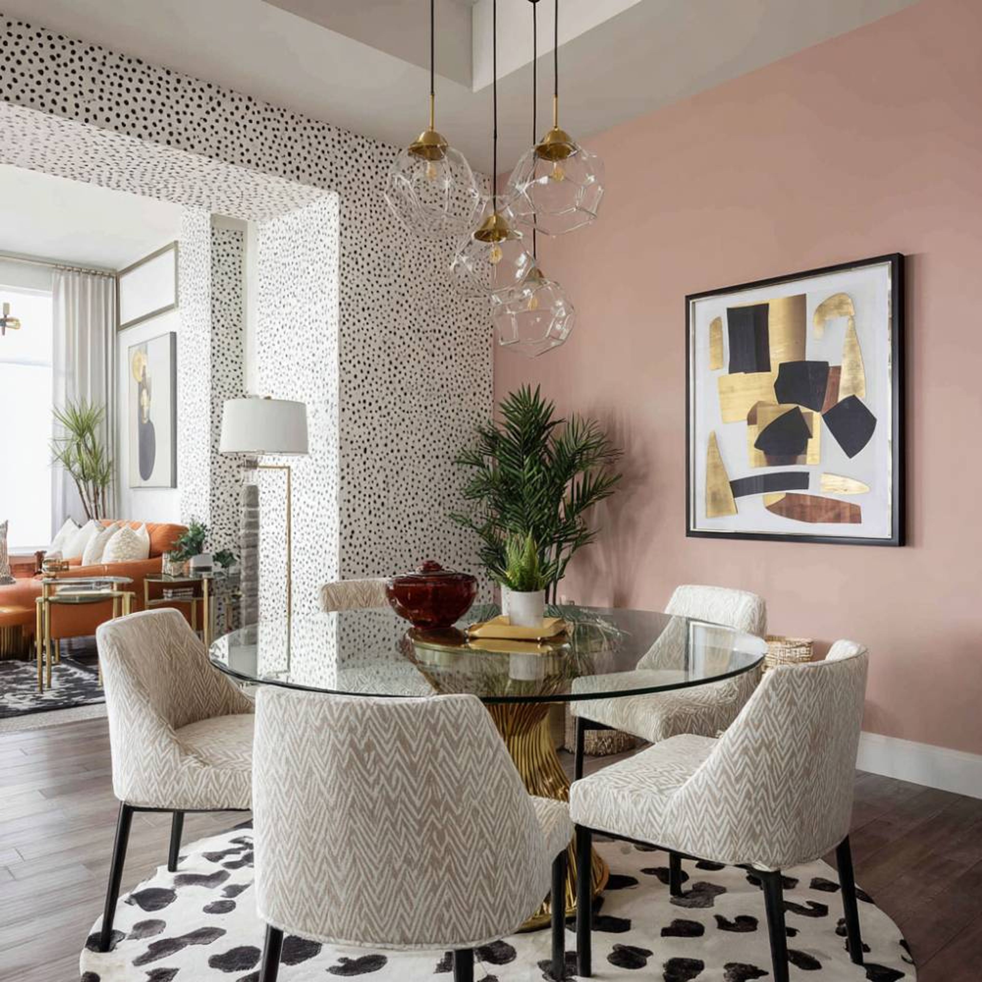 Dining room with blush walls, gold base glass table, and patterned chairs