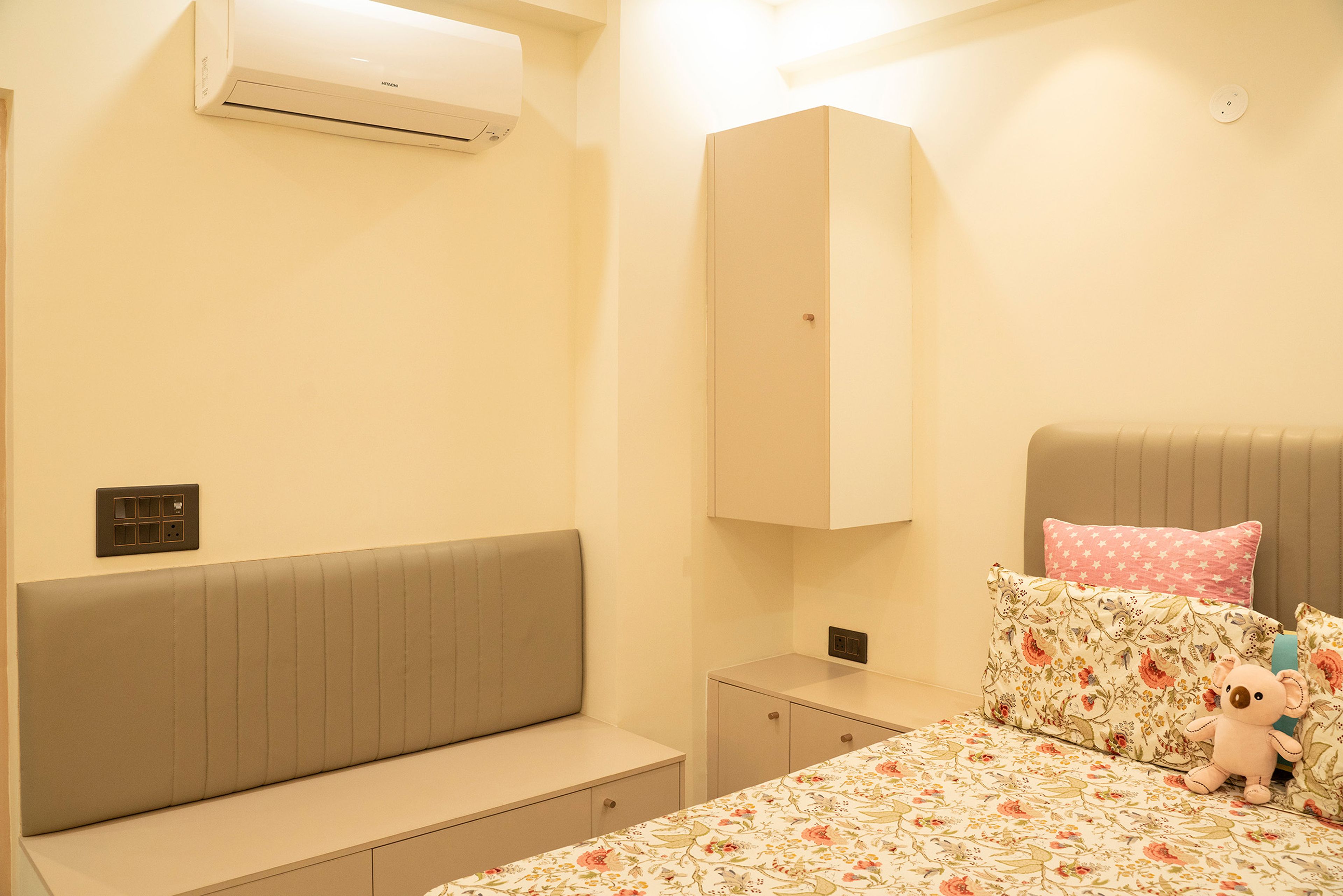 Guest bedroom with floral bedding, soft beige walls, and floor-to-ceiling built-in wardrobe