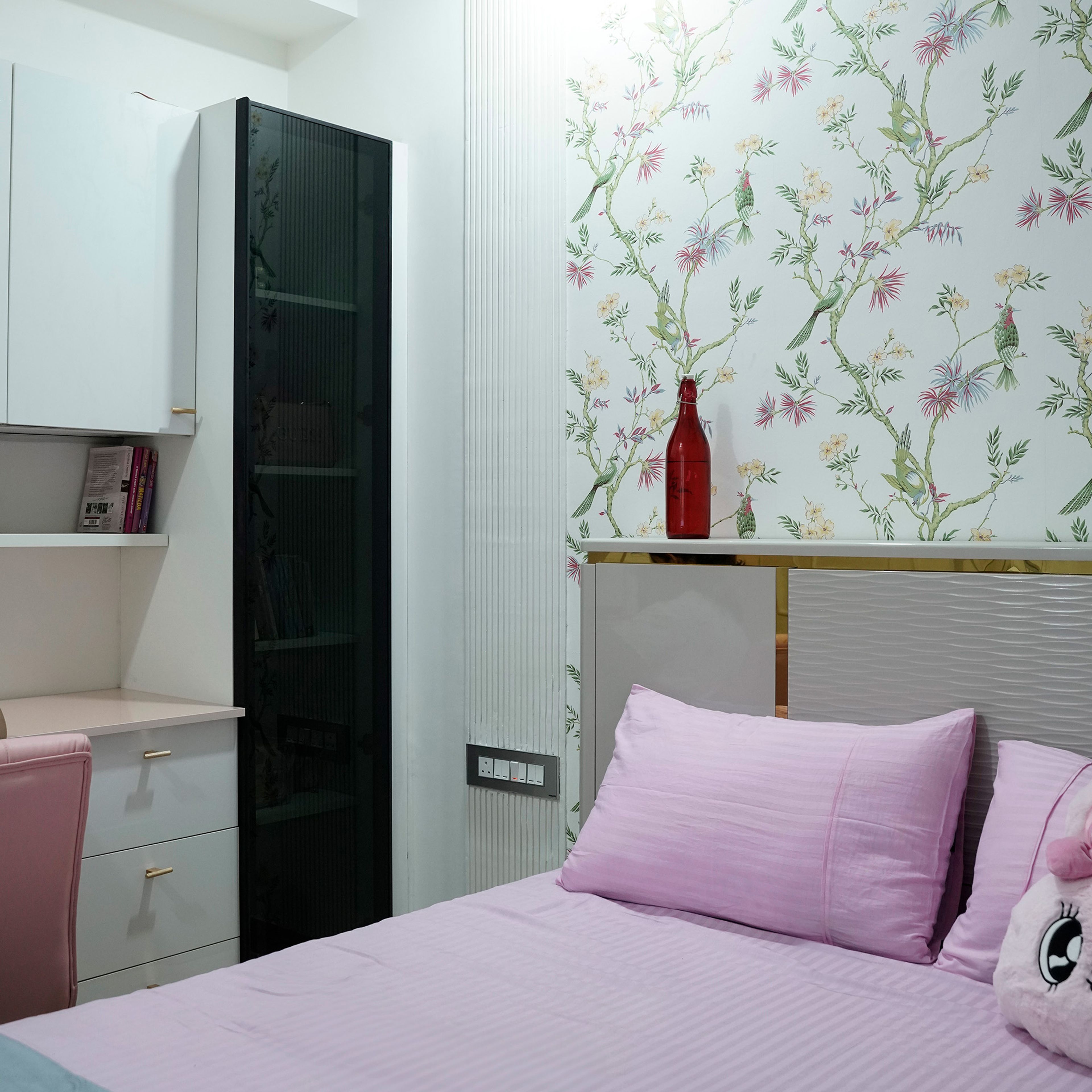 Kids’ bedroom with botanical wall art, pink bedding, soft curtains, and modern side table