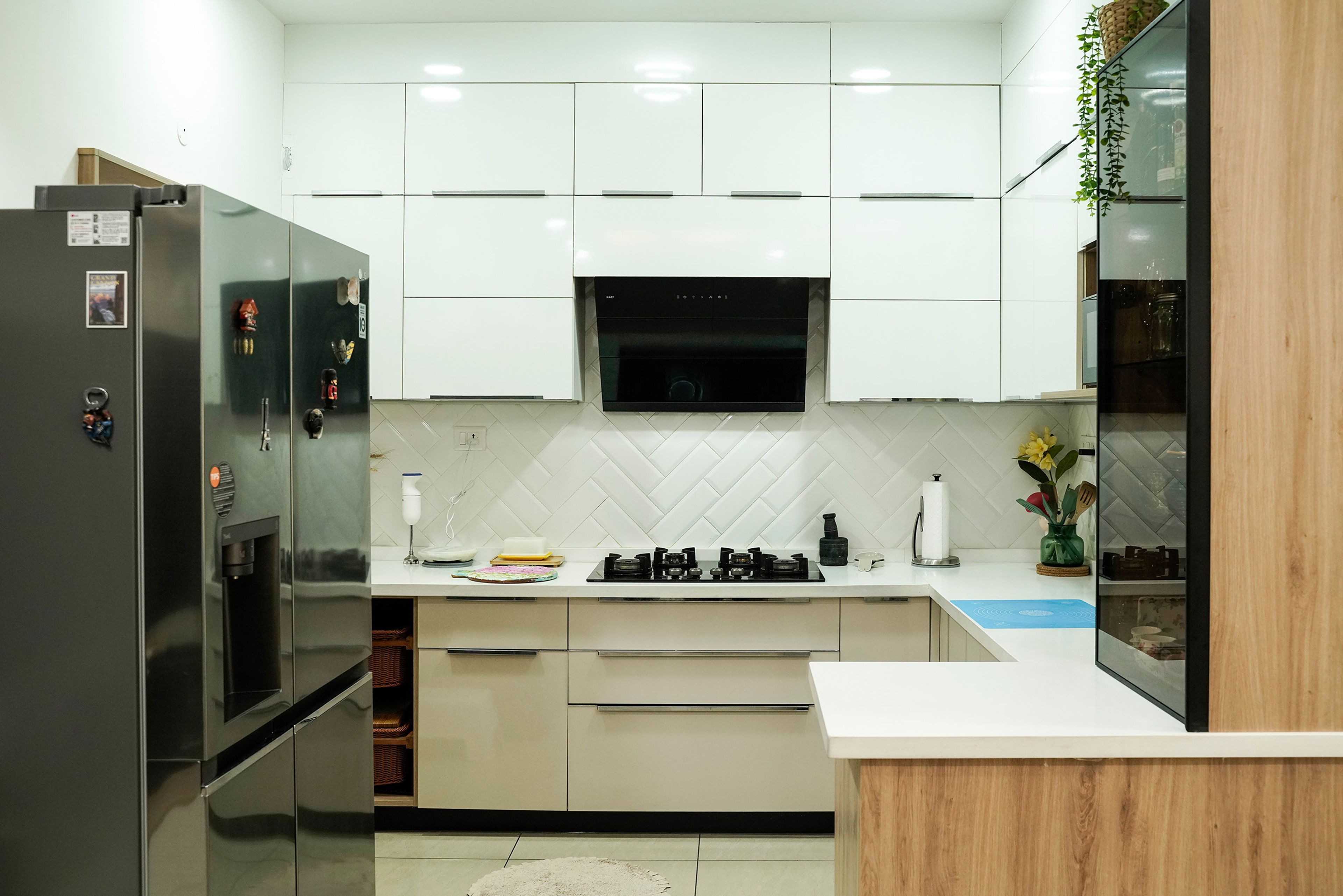 U-Shaped white kitchen with herringbone backsplash, glass cabinet, and built-in chimney