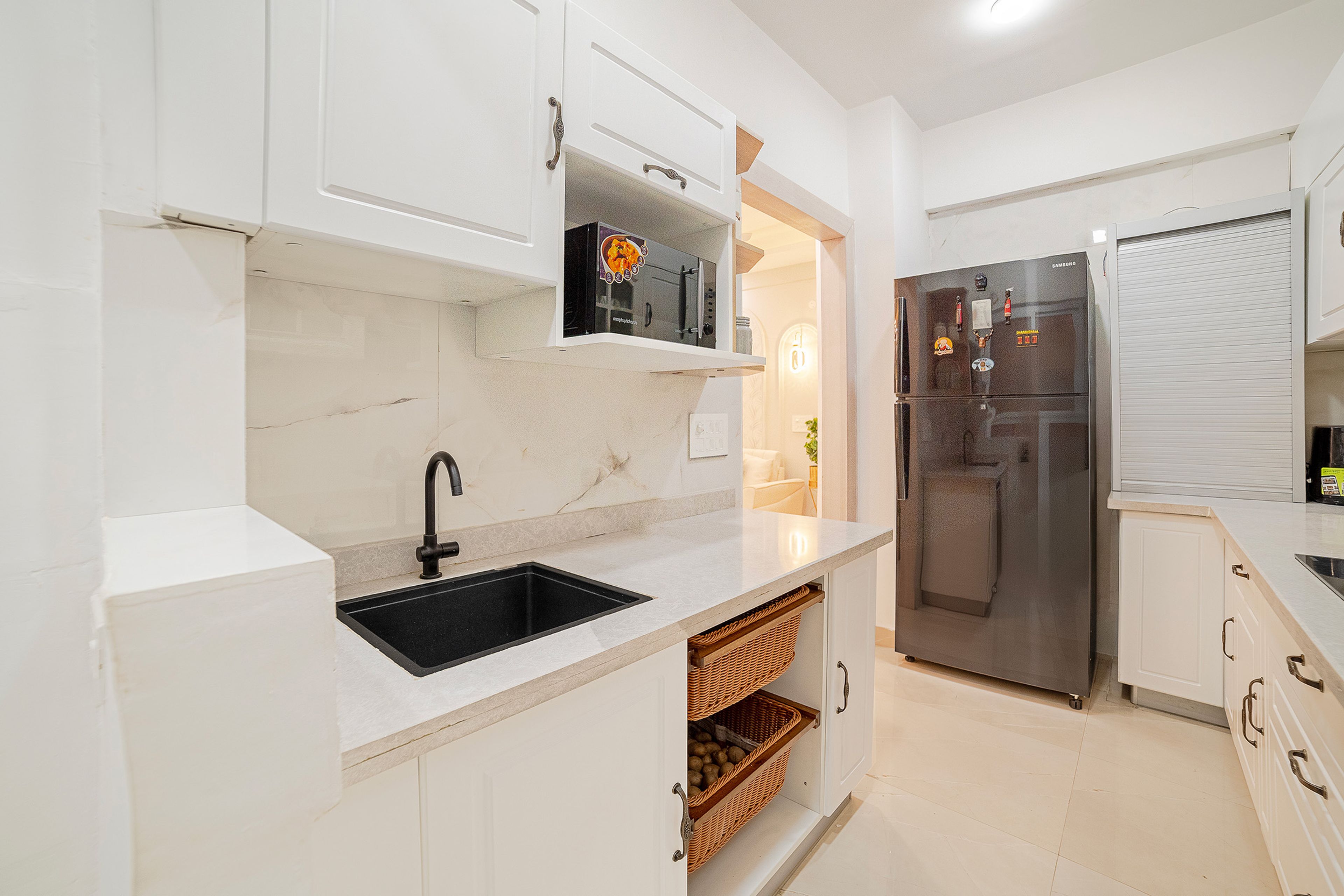 Off- white parallel kitchen with glass-front cabinets, black chimney, and secondary washing area