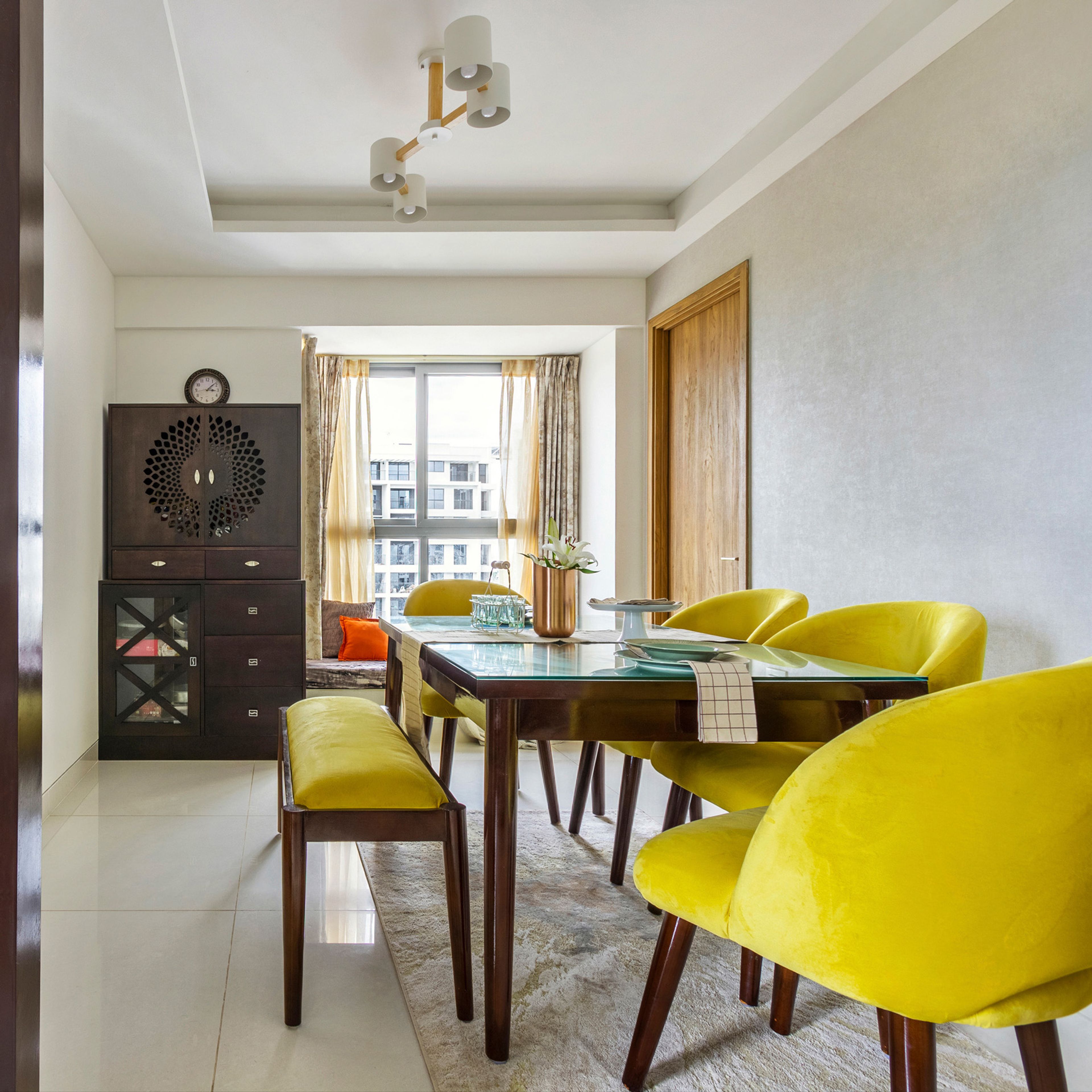 Dining Room Design With 4 Yellow Chairs, Wooden Table, Wooden Integrated Mandir Unit And Storage - Livspace
