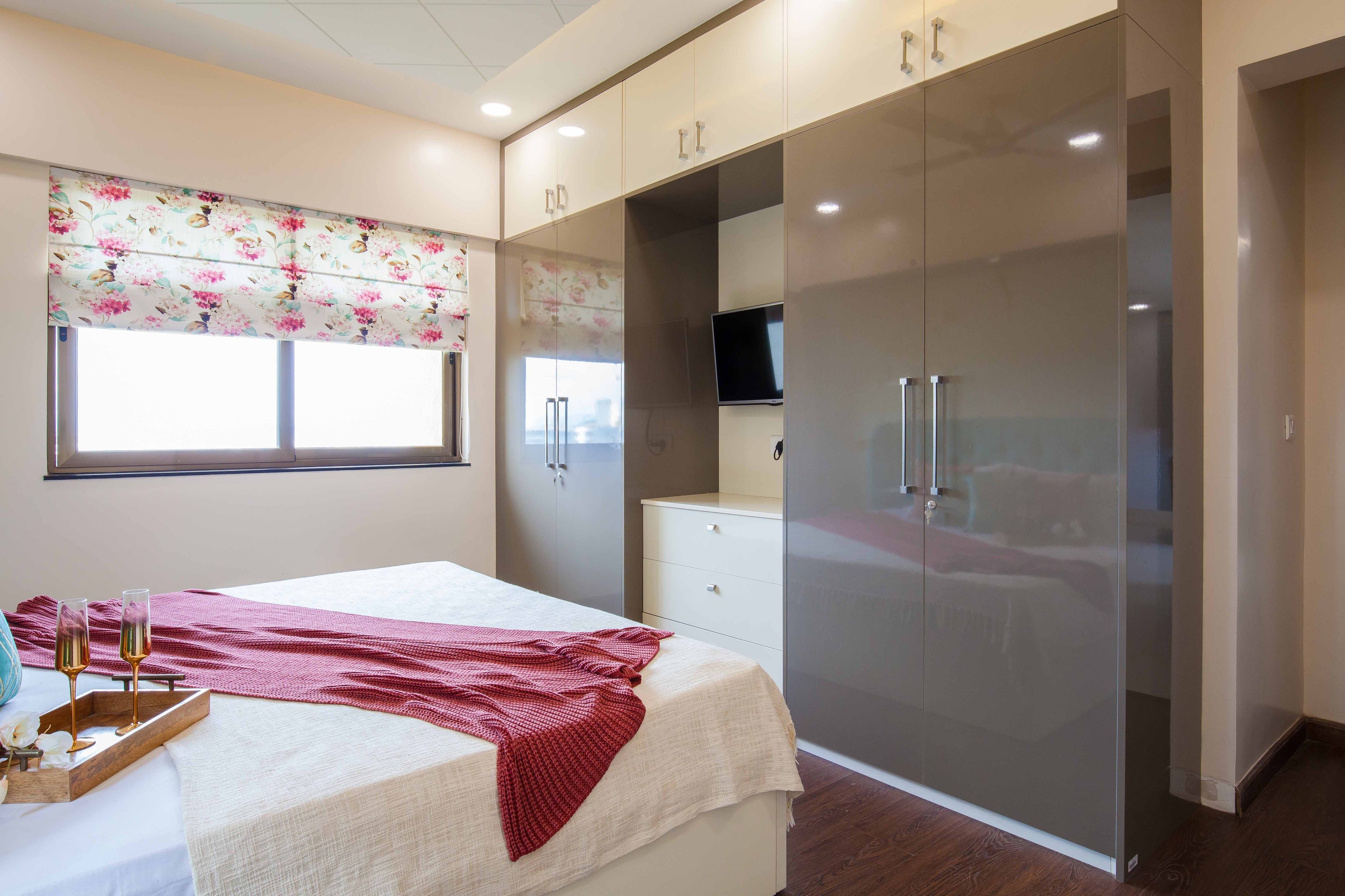 Serenely Coastal Guest Room Design With Queen Bed, Floral Wallpaper, Dark Grey Wardrobe, and White Side Tables - Livspace