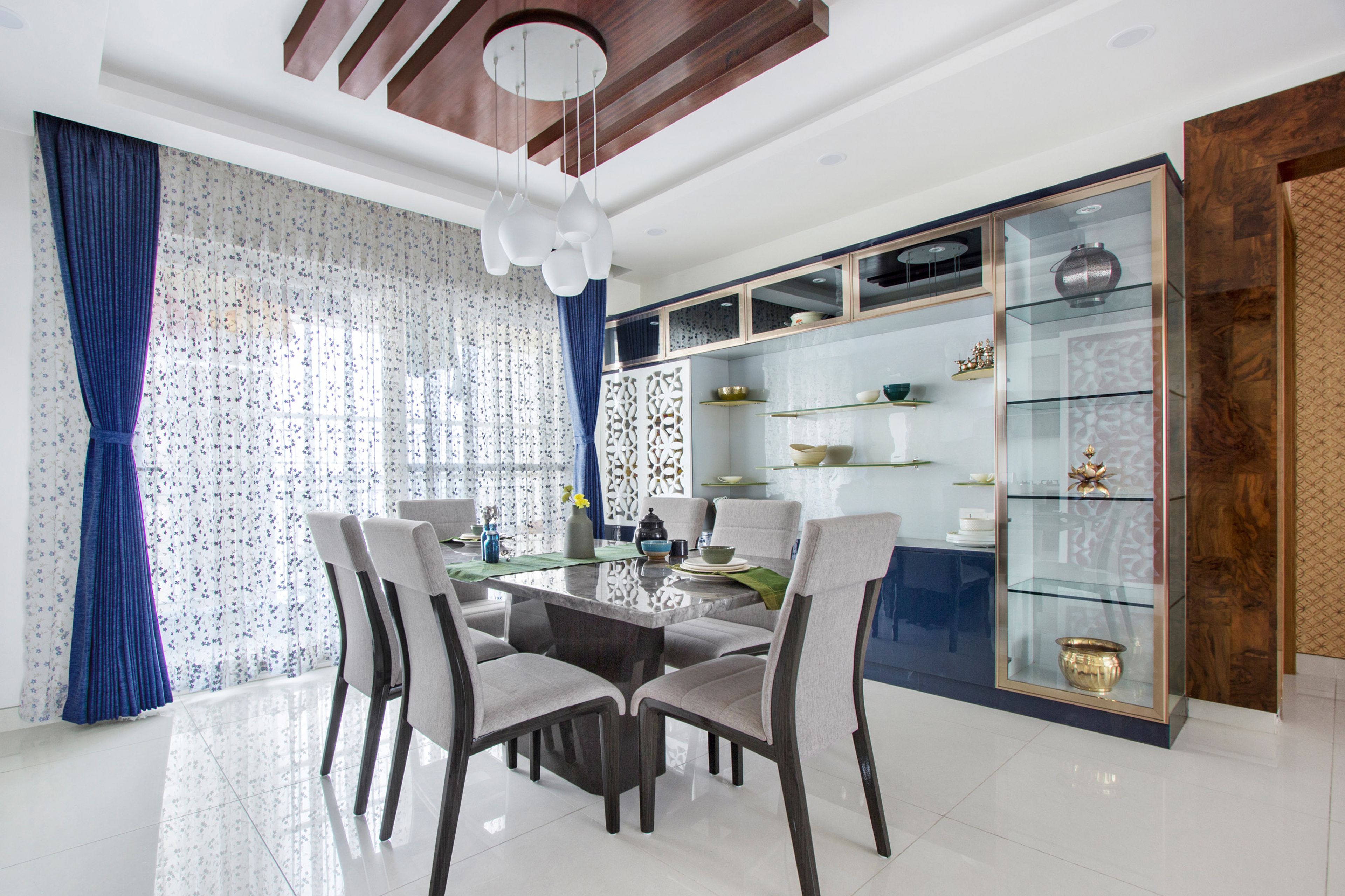 Dining room design with 6 seater dining table, chairs and glass cabinet - Livspace