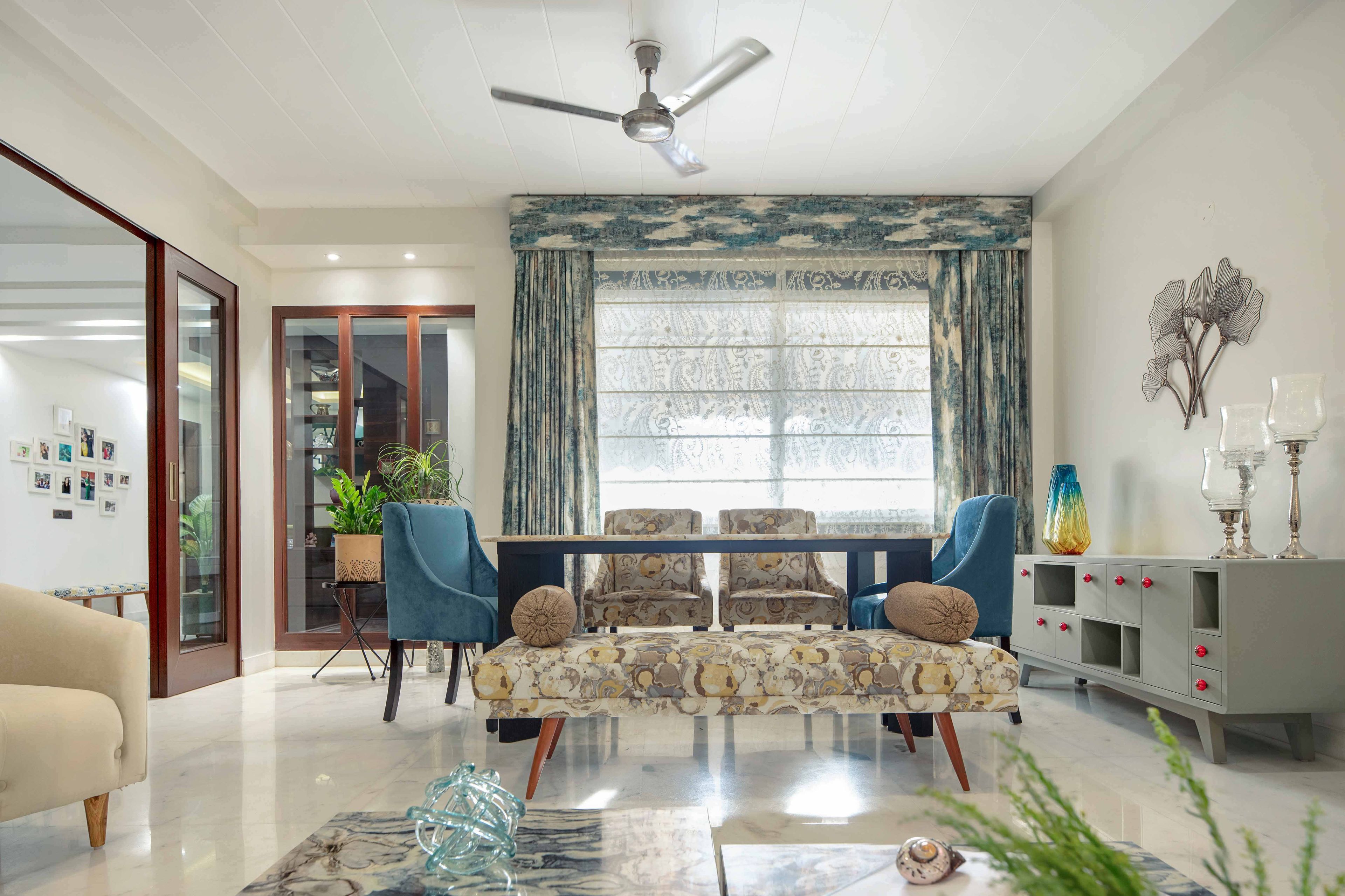 Dining room design with white dining table, blue and white chairs, and crockery unit - Livspace