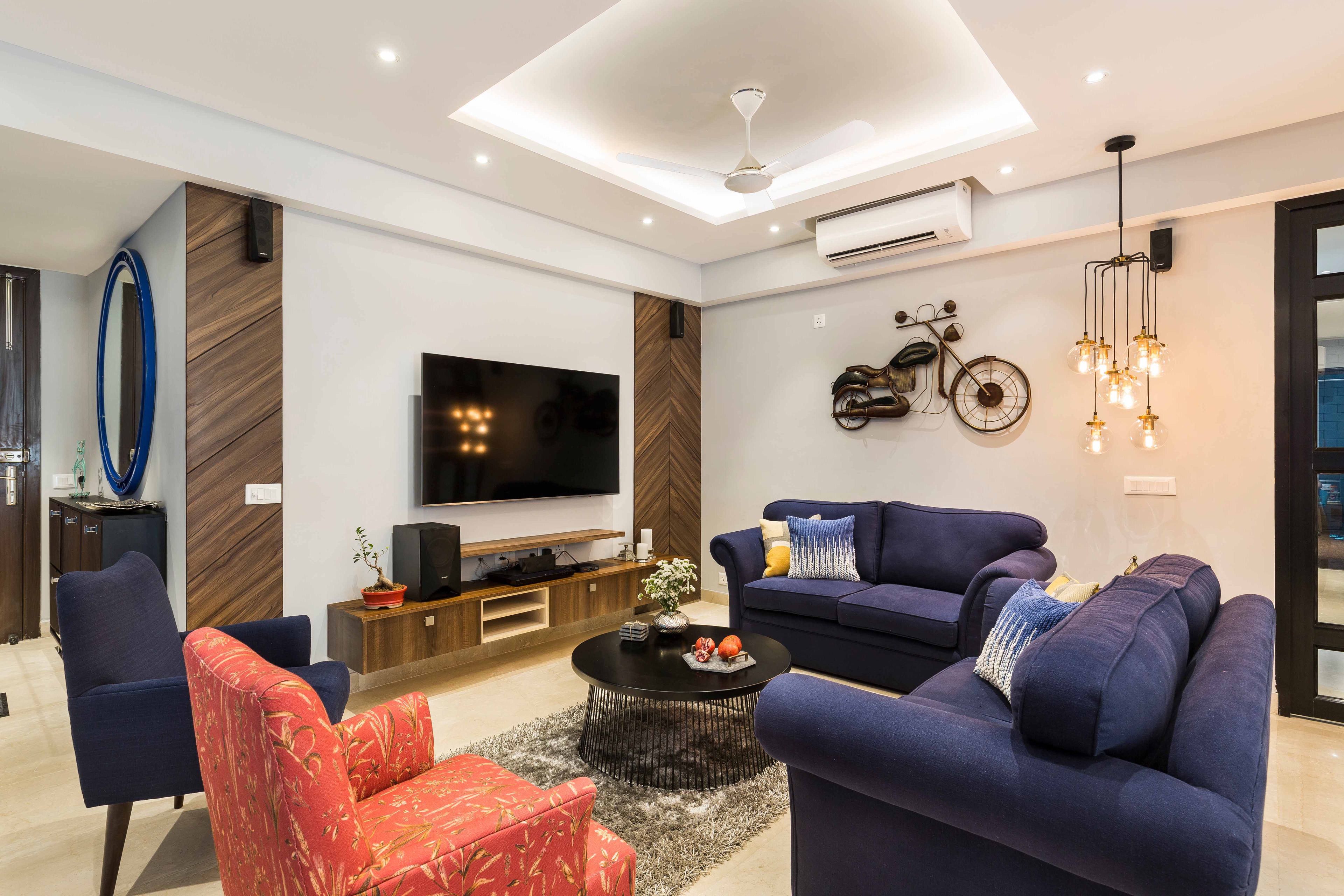 Contemporary Living Room with L-Shape Dark Blue Sofa Set, Red Patterned Accent Chair, and Wall-mounted TV Console - Livspace