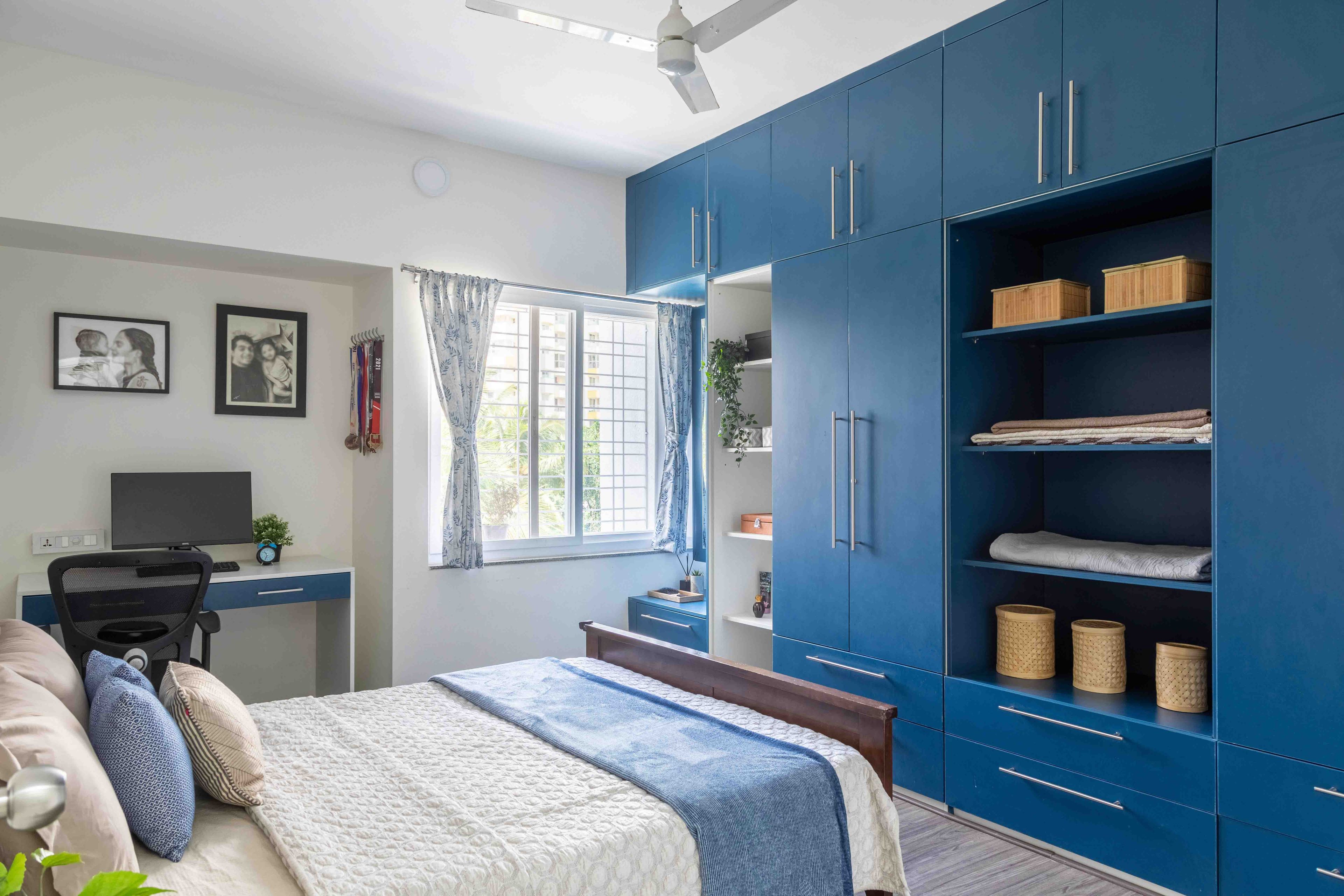 Master Bedroom Design With Blue Swing Wardrobe Design And Open Shelves - Livspace