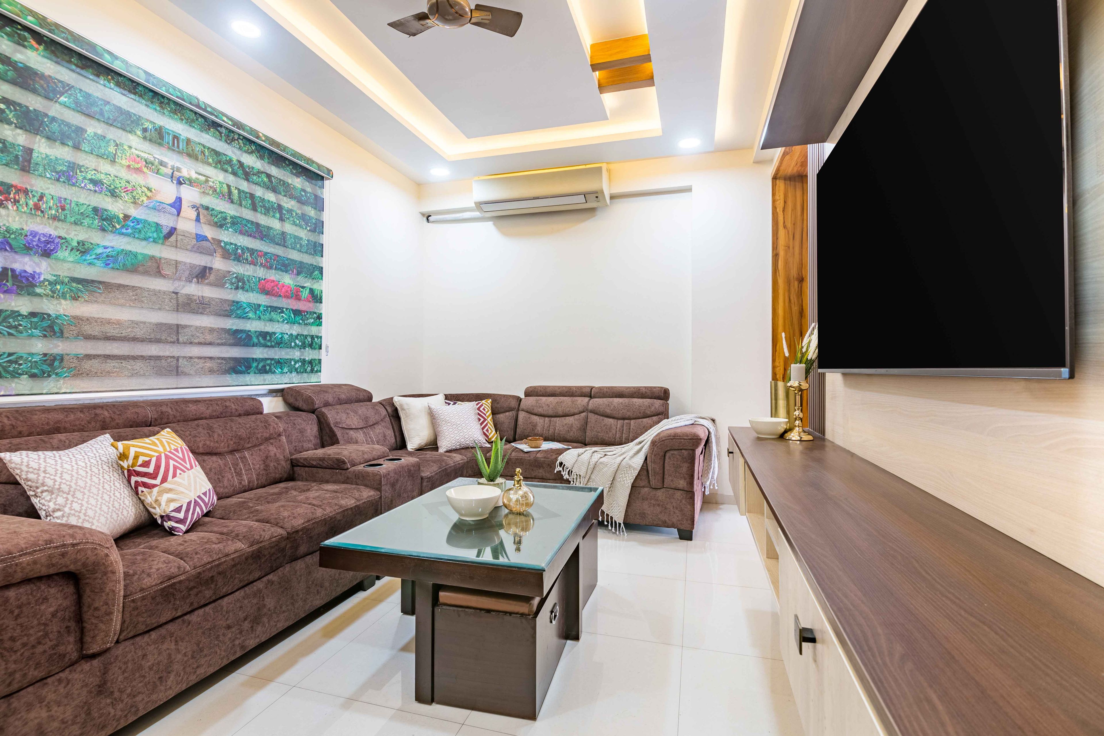 Spacious Living Room Design With Brown L-Shaped Seater And Peacock Shutters - Livspace