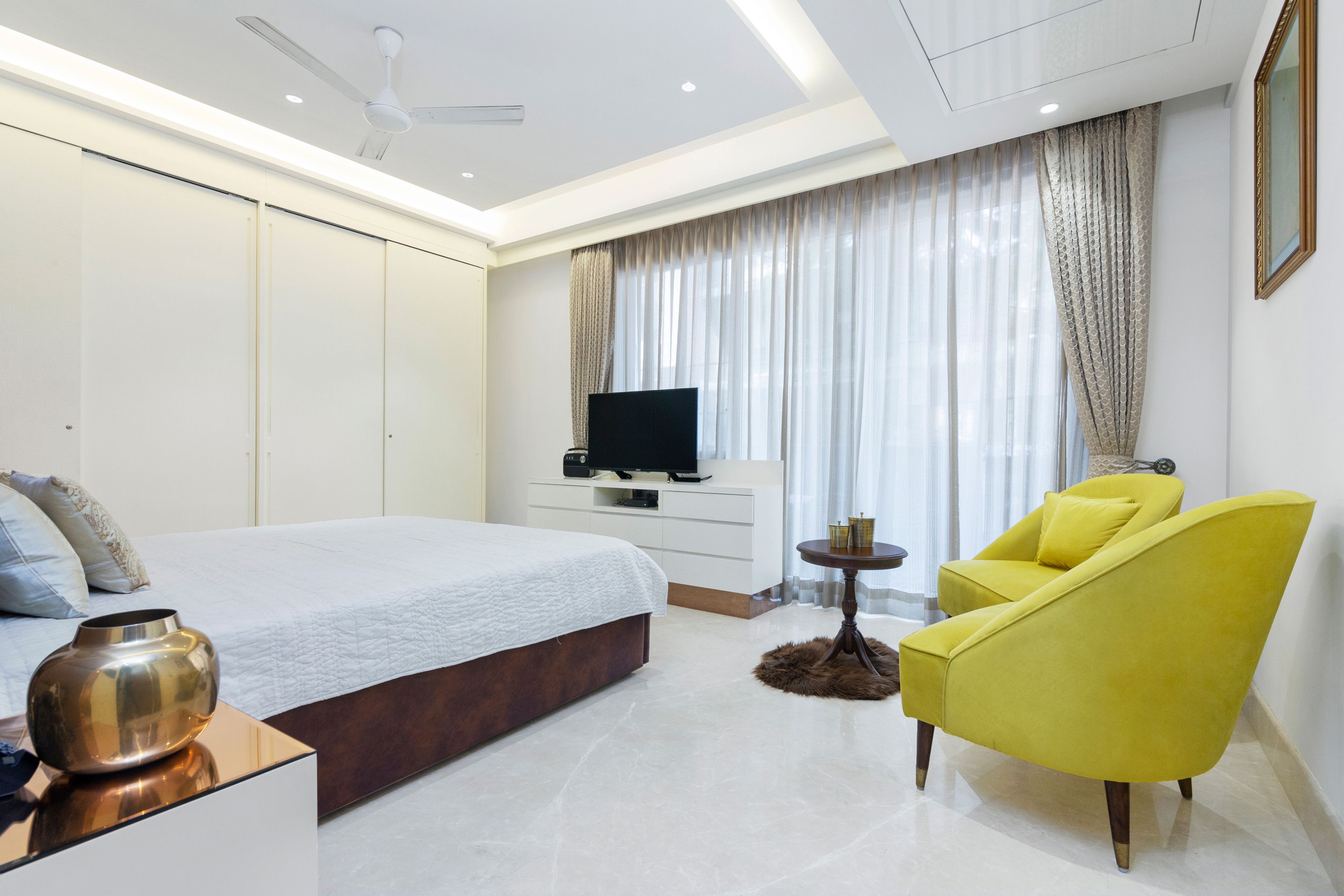 White Guest Room Design With White Sliding Wardrobe And Neon Green Accent Chairs - Livspace