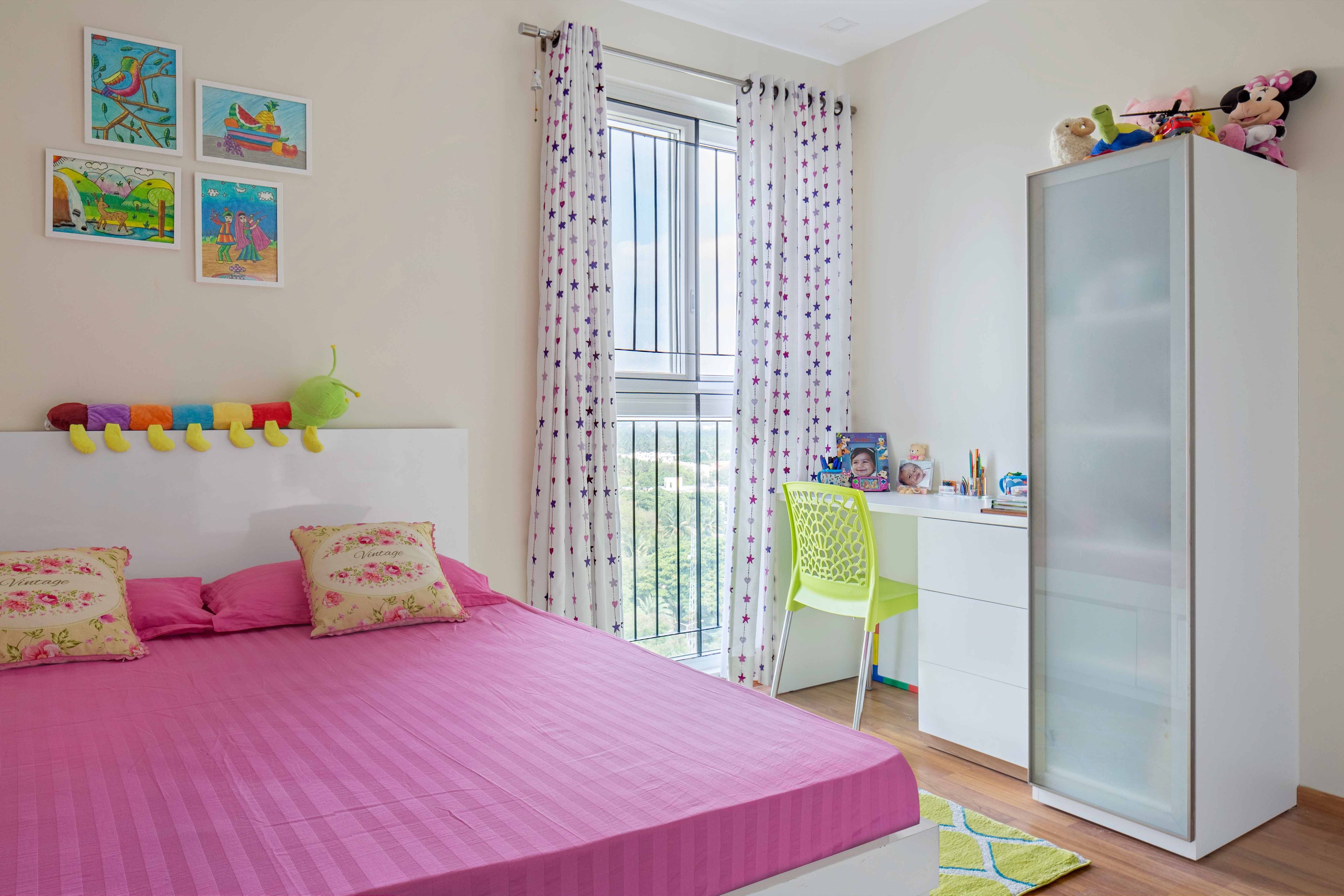 Pink kids bedroom design with white study table and storage unit - Livspace