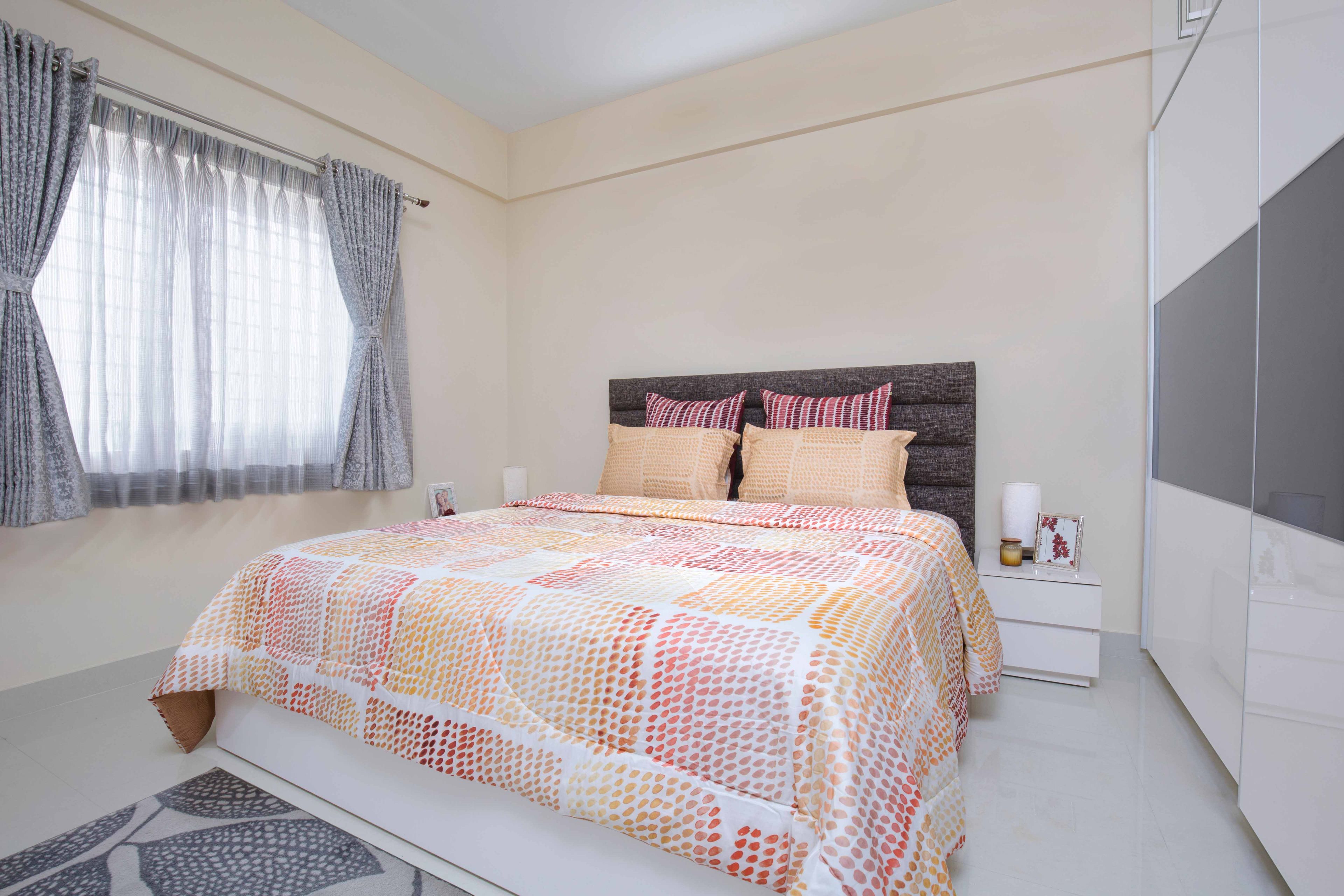 Master bedroom design with multi-coloured upholstery and white and grey sliding wardrobe - Livspace