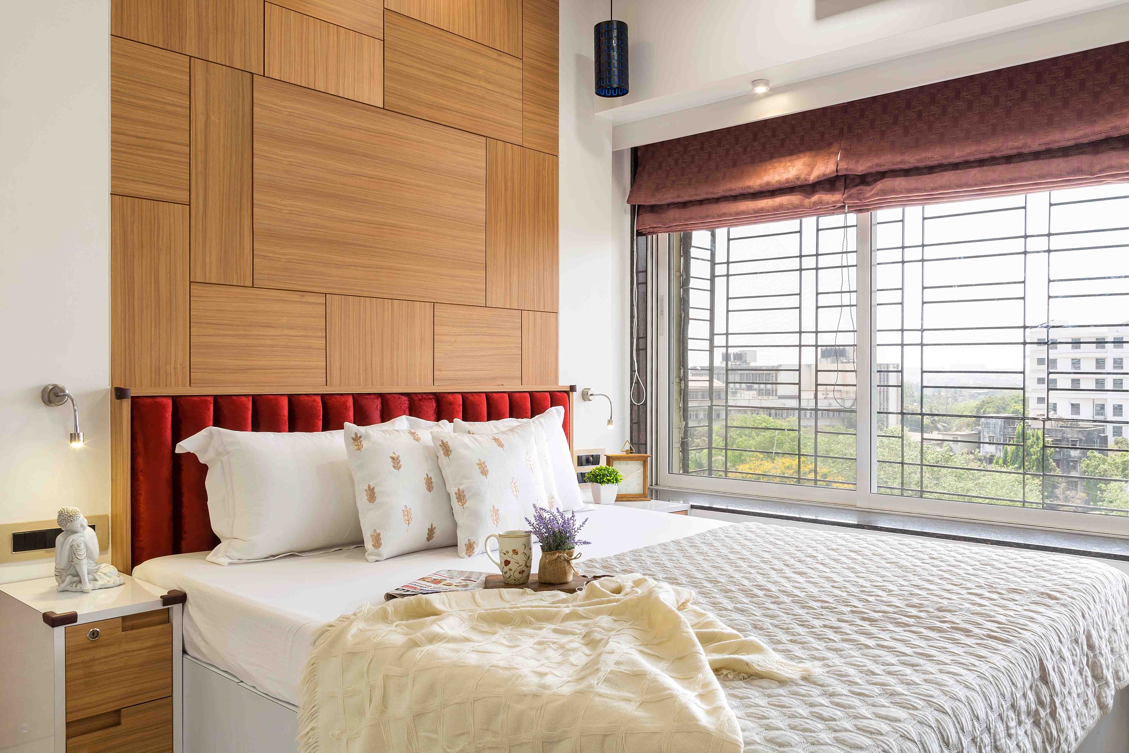 Master bedroom design with red tufted headboard and wooden wall panel - Livspace