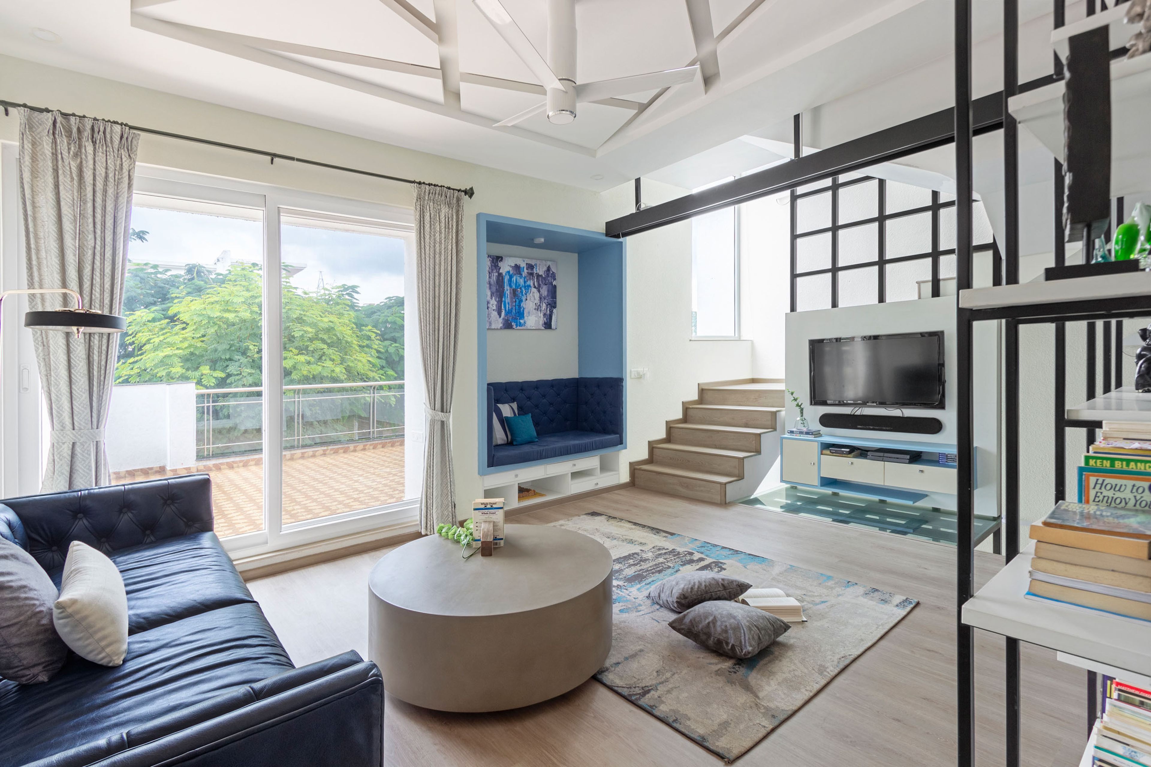 Spacious blue and grey living room design with wall niche and wall seater - Livspace