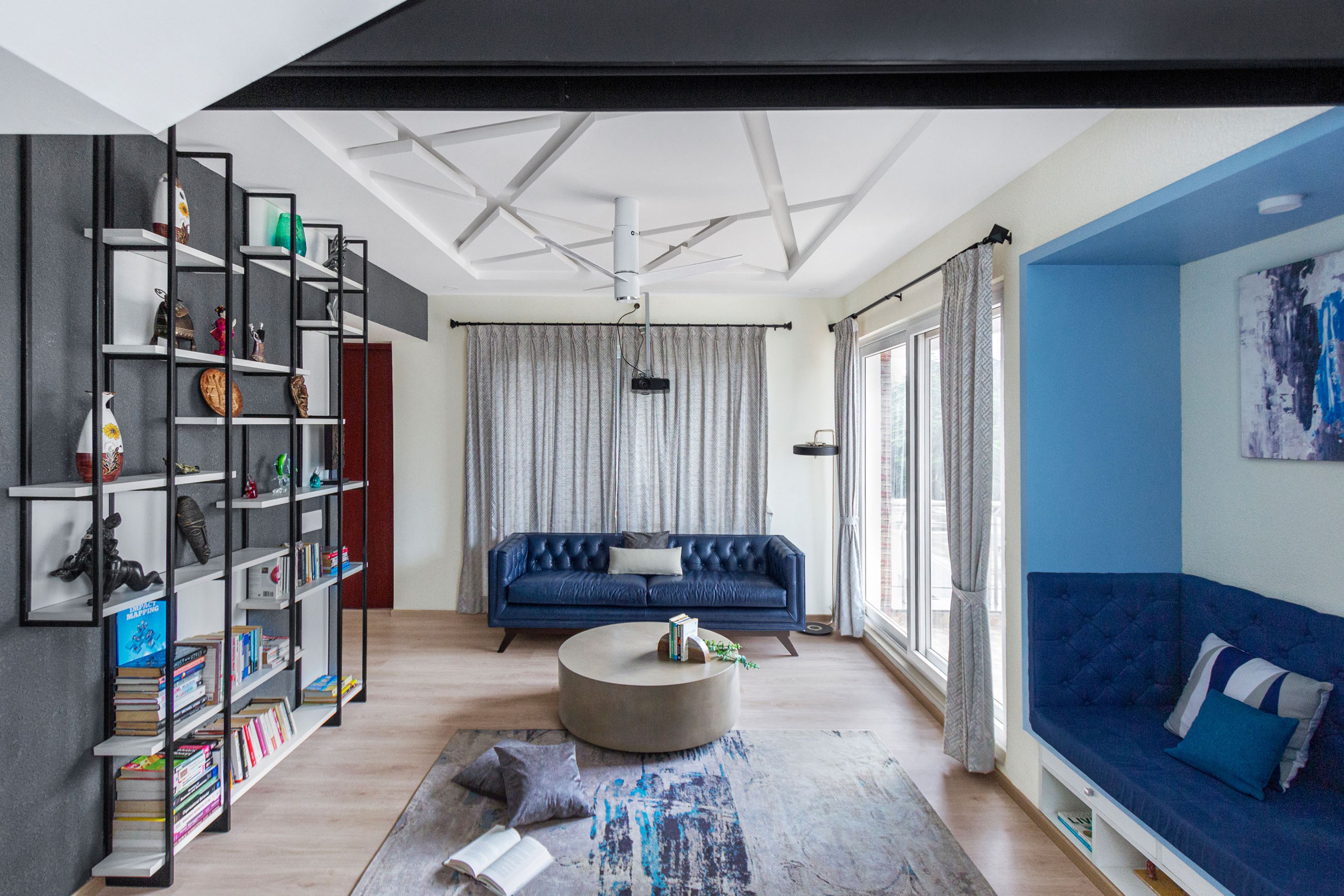 Blue and grey living room design with open bookshelf - Livspace