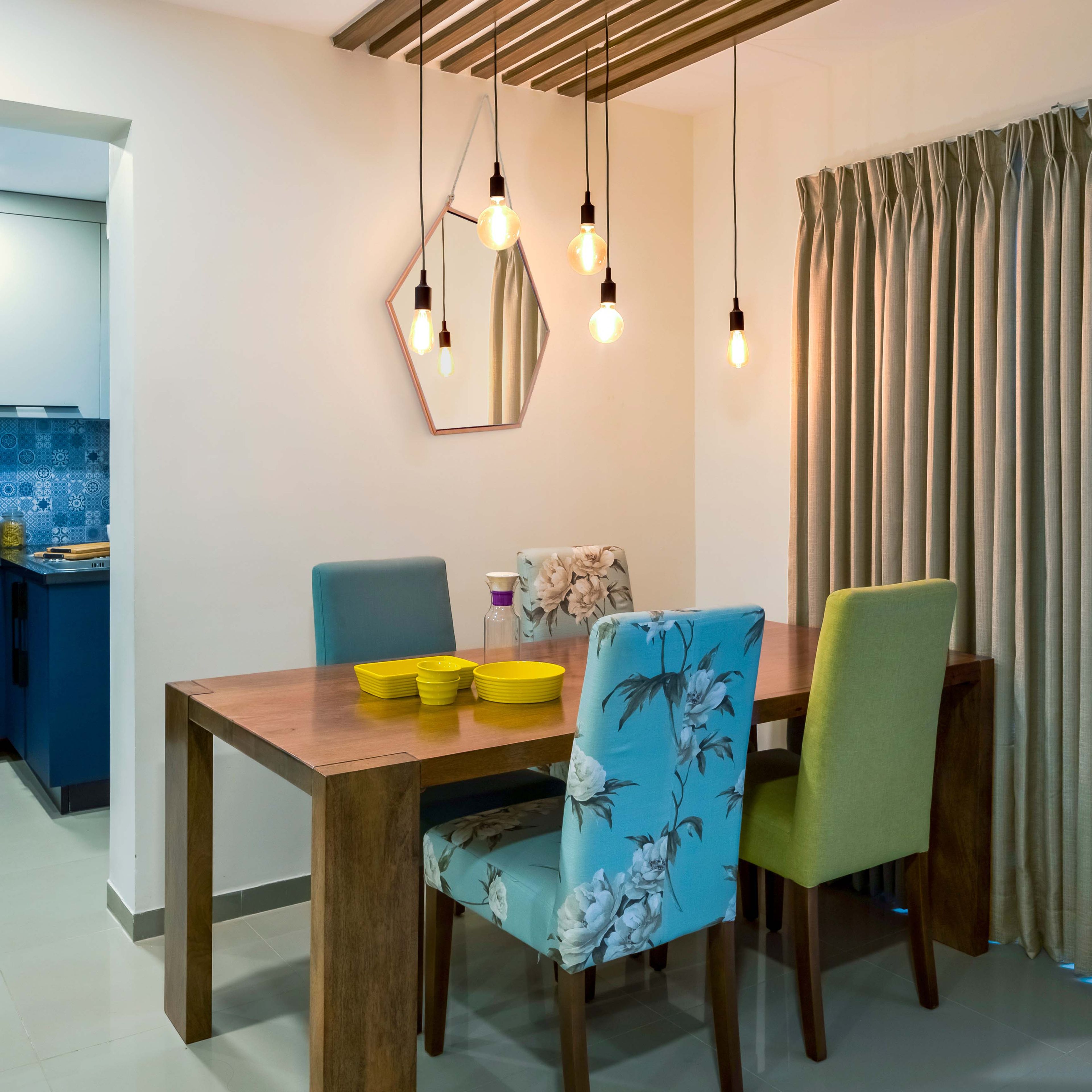 4-seater wooden dining room design with floral accent chairs and drop lights - Livspace