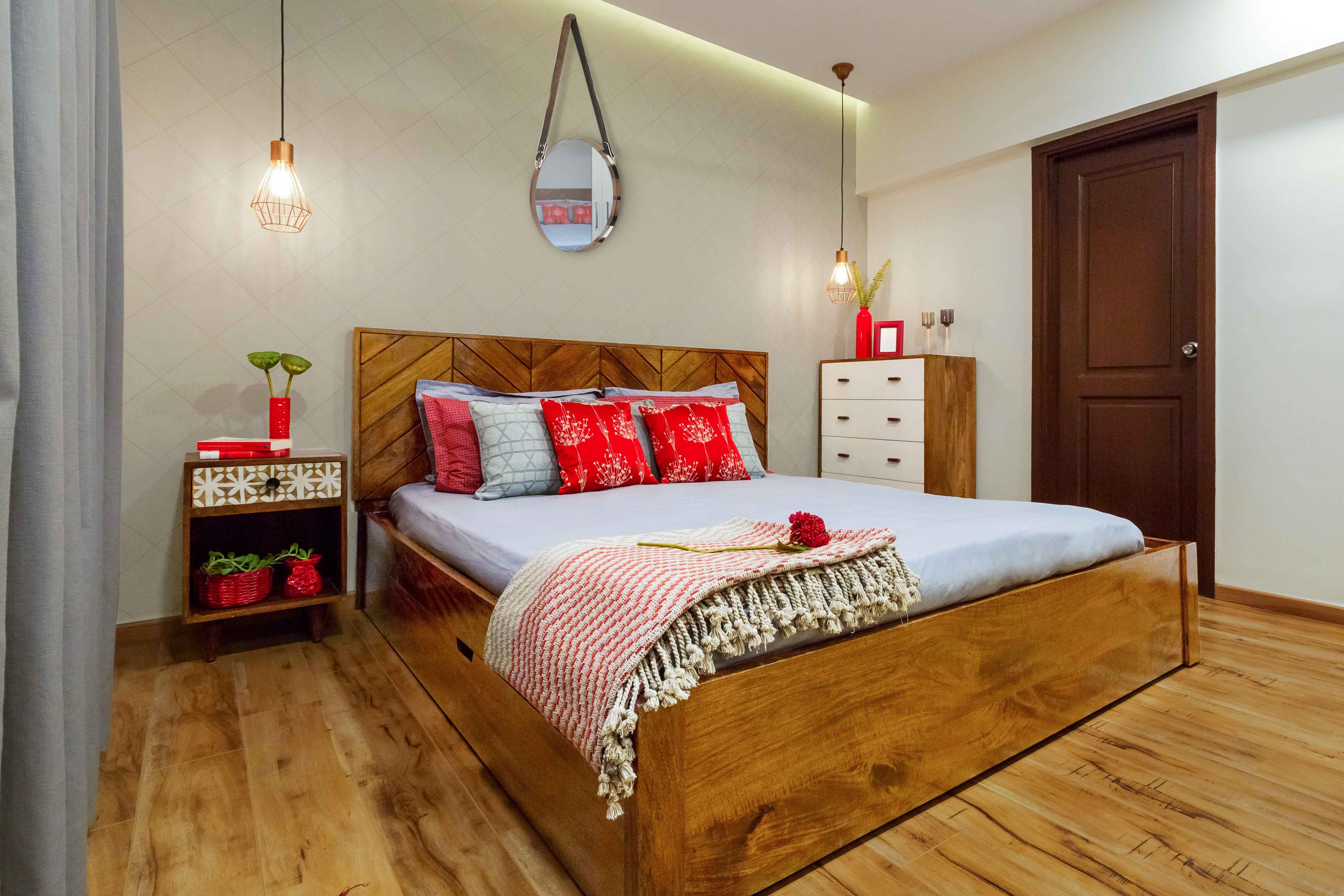 Wood and white guest room design with red pillows and drop lights - Livspace