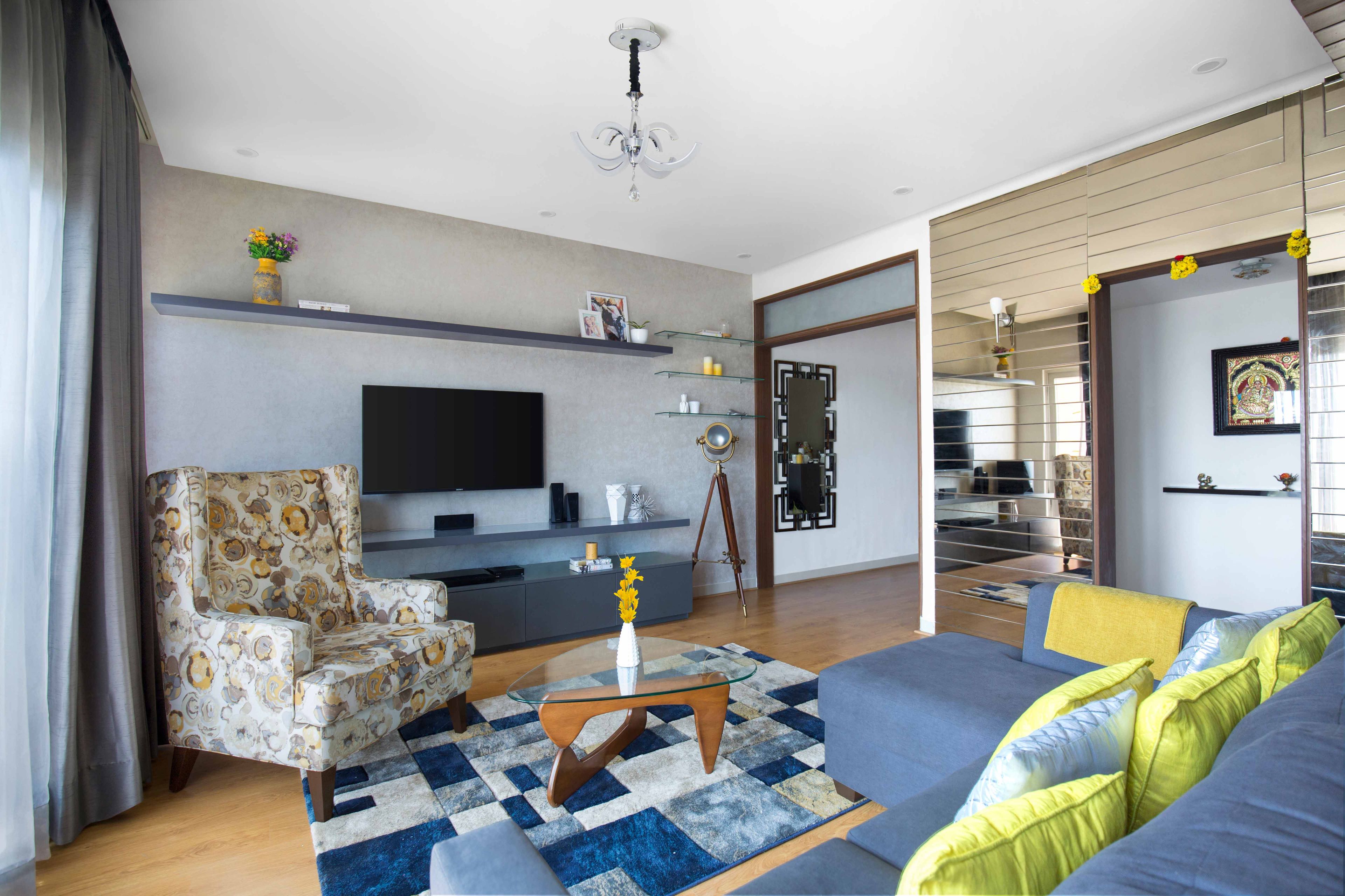 Grey and yellow living room design with accent chair, gold wall panelling and TV unit - Livspace