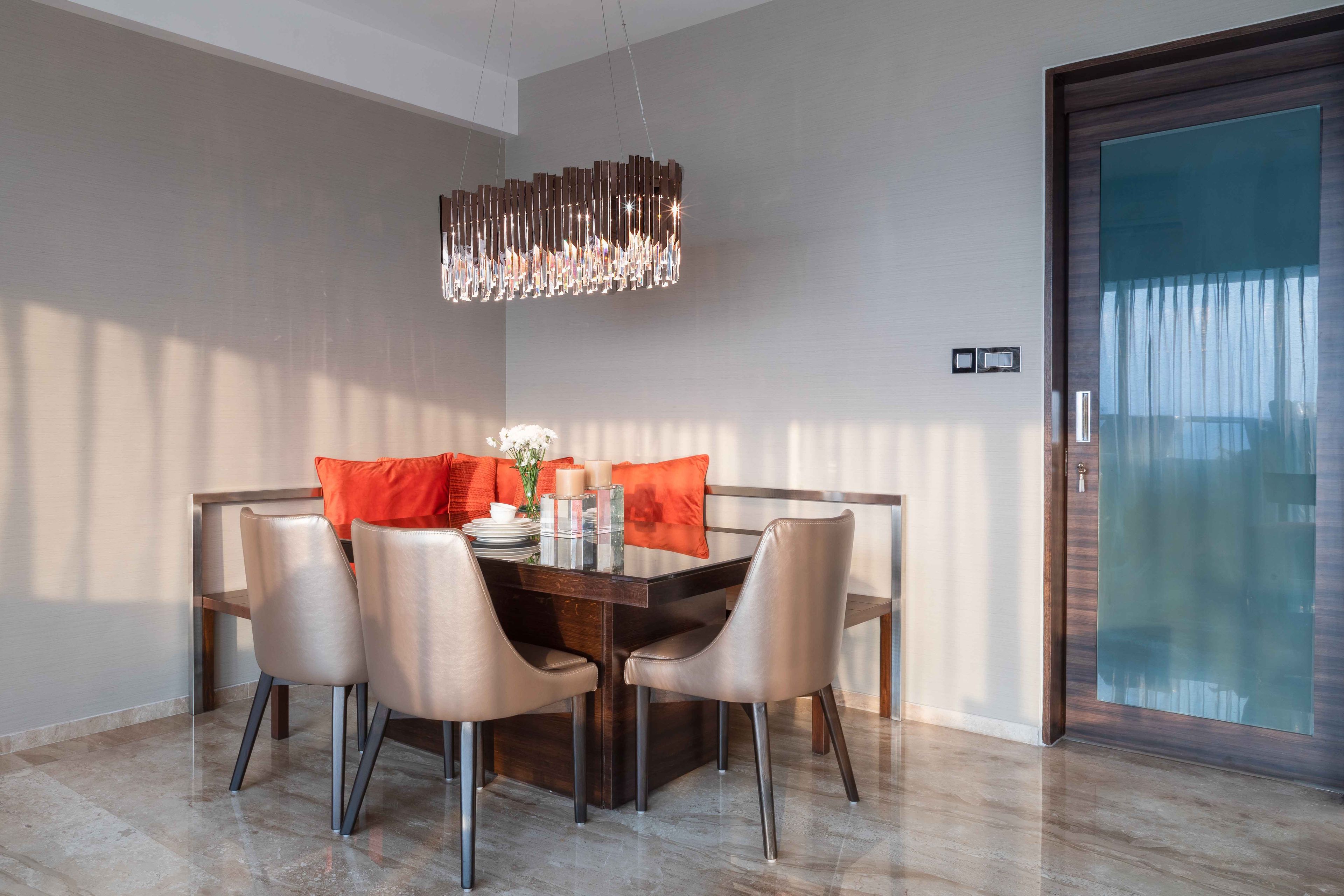 3-seater wooden dining room design with L-shaped seater and oramental lights - Livspace