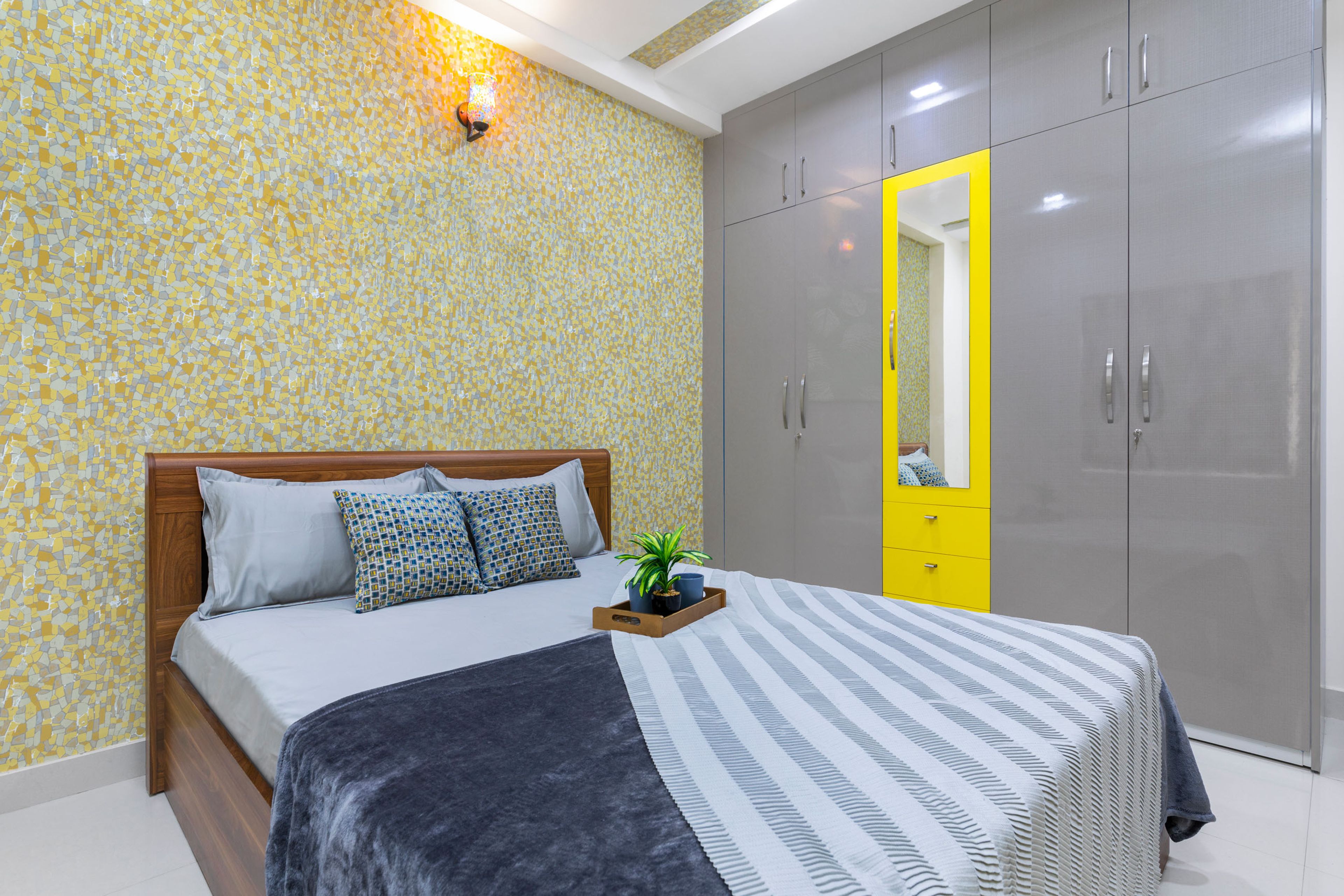 Guest Bedroom With Wooden Bed, 4-Door Grey And Yellow Swing Wardrobe And Mosaic Wallpaper - Livspace