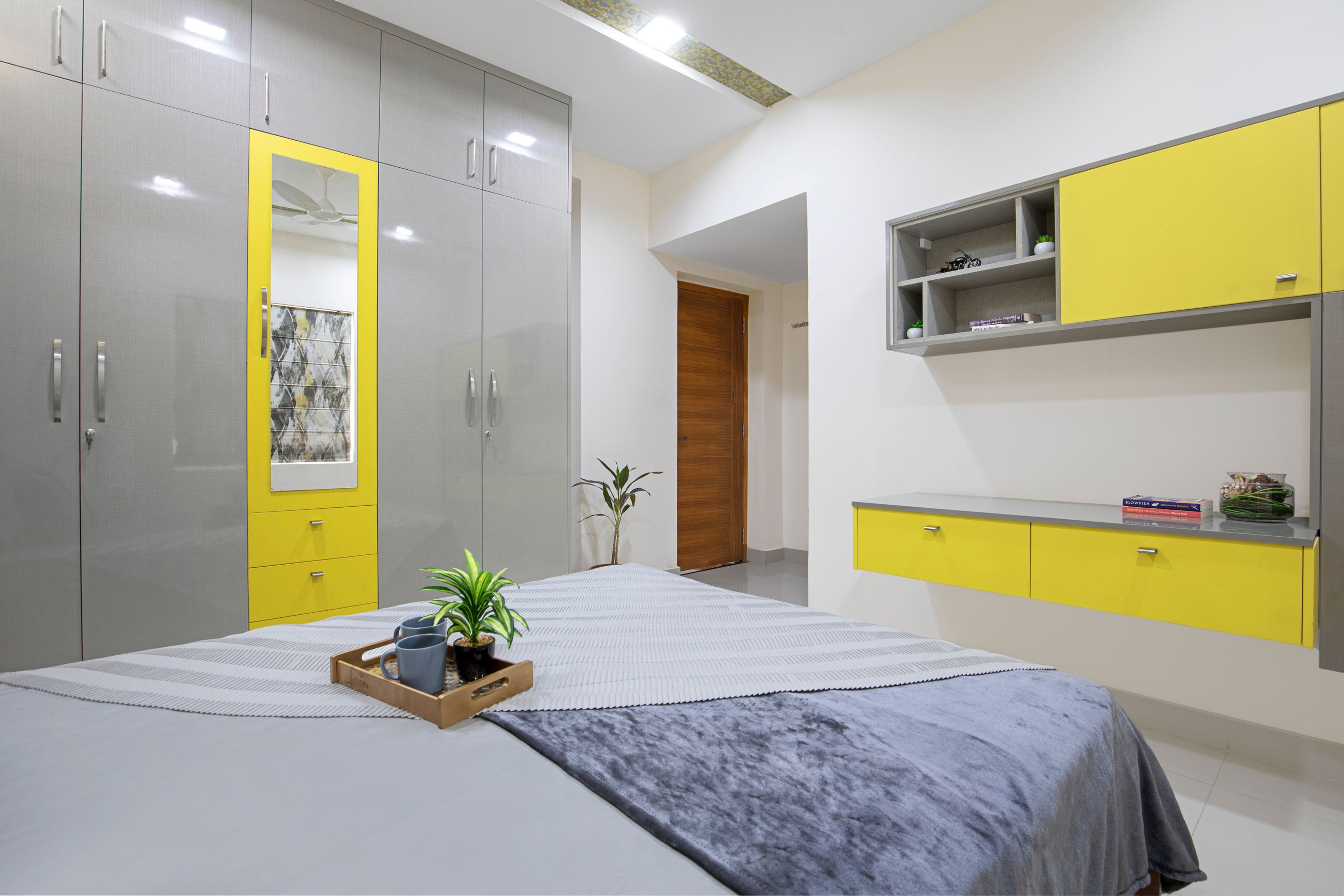 Spacious Guest Bedroom With Grey And Yellow Wall-Mounted Study Table And 4-Door Swing Wardrobe - Livspace