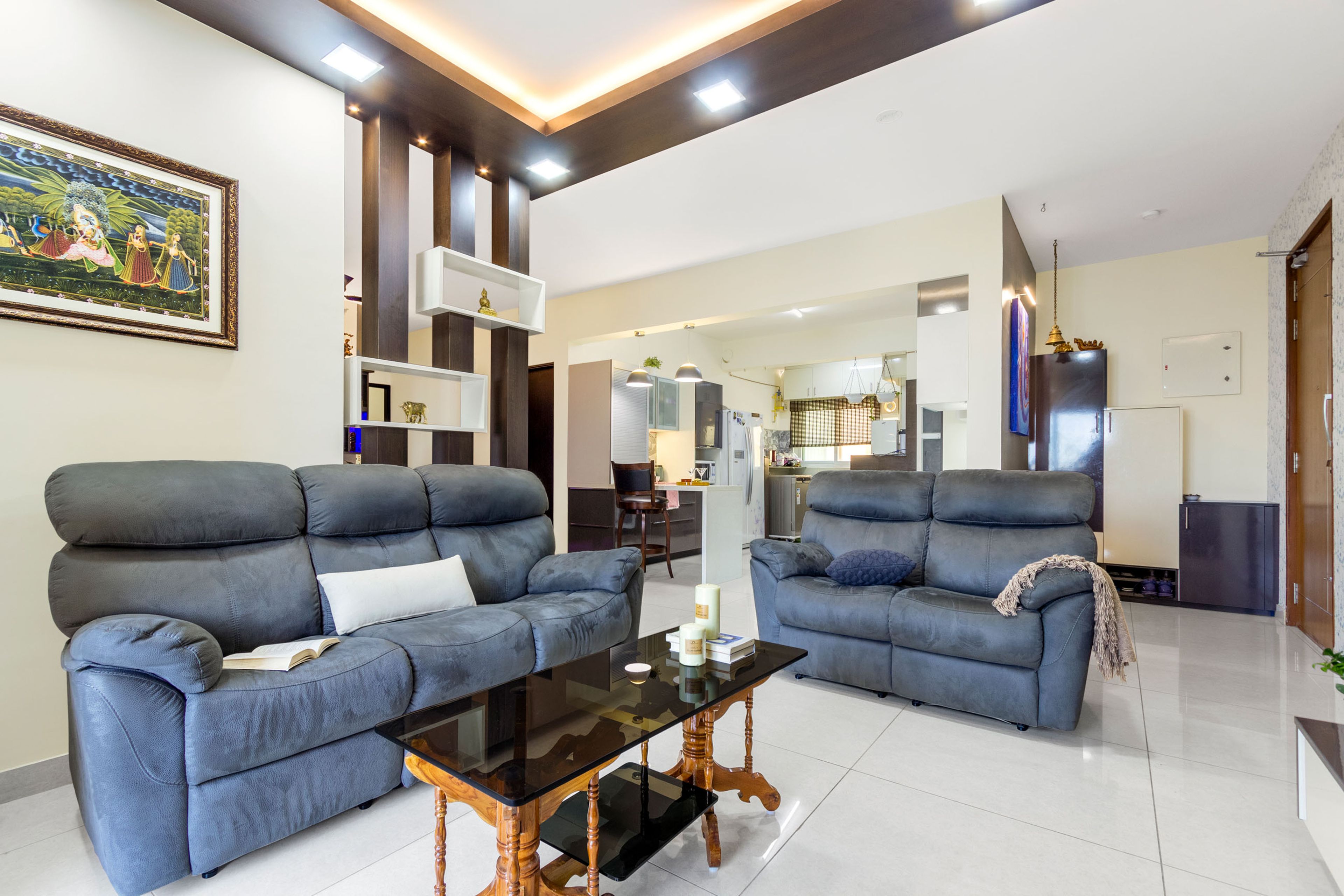 Living room design with L-shaped velvet sofas and wooden rectangular coffee table and black glass countertop - Livspace