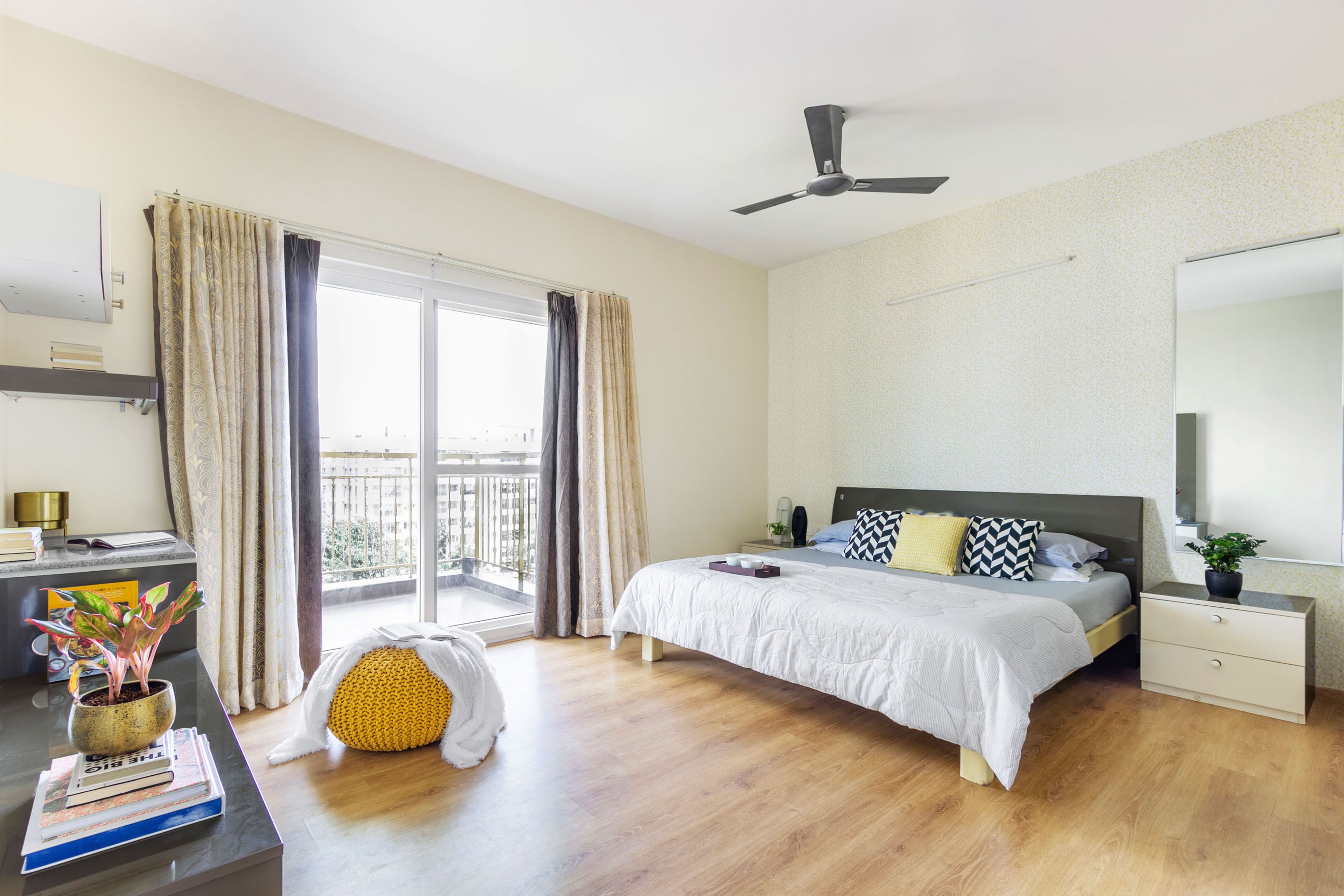 Spacious Master Bedroom Design With Balcony, Wooden Flooring And Beige Patterned Wall - Livspace