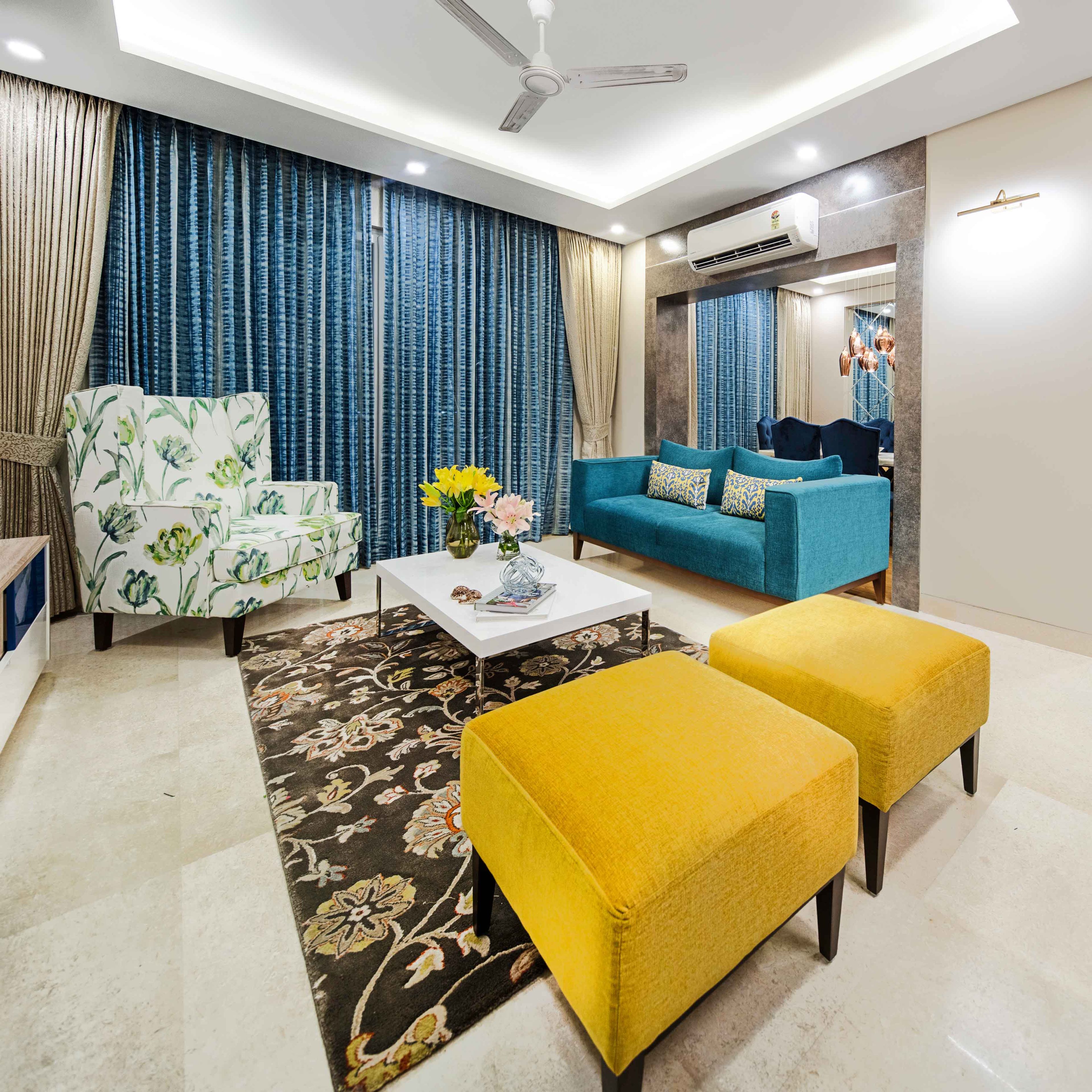 Living Room Design With Blue Sofa, Yellow Ottomans, And Floral Accent Chair - Livspace