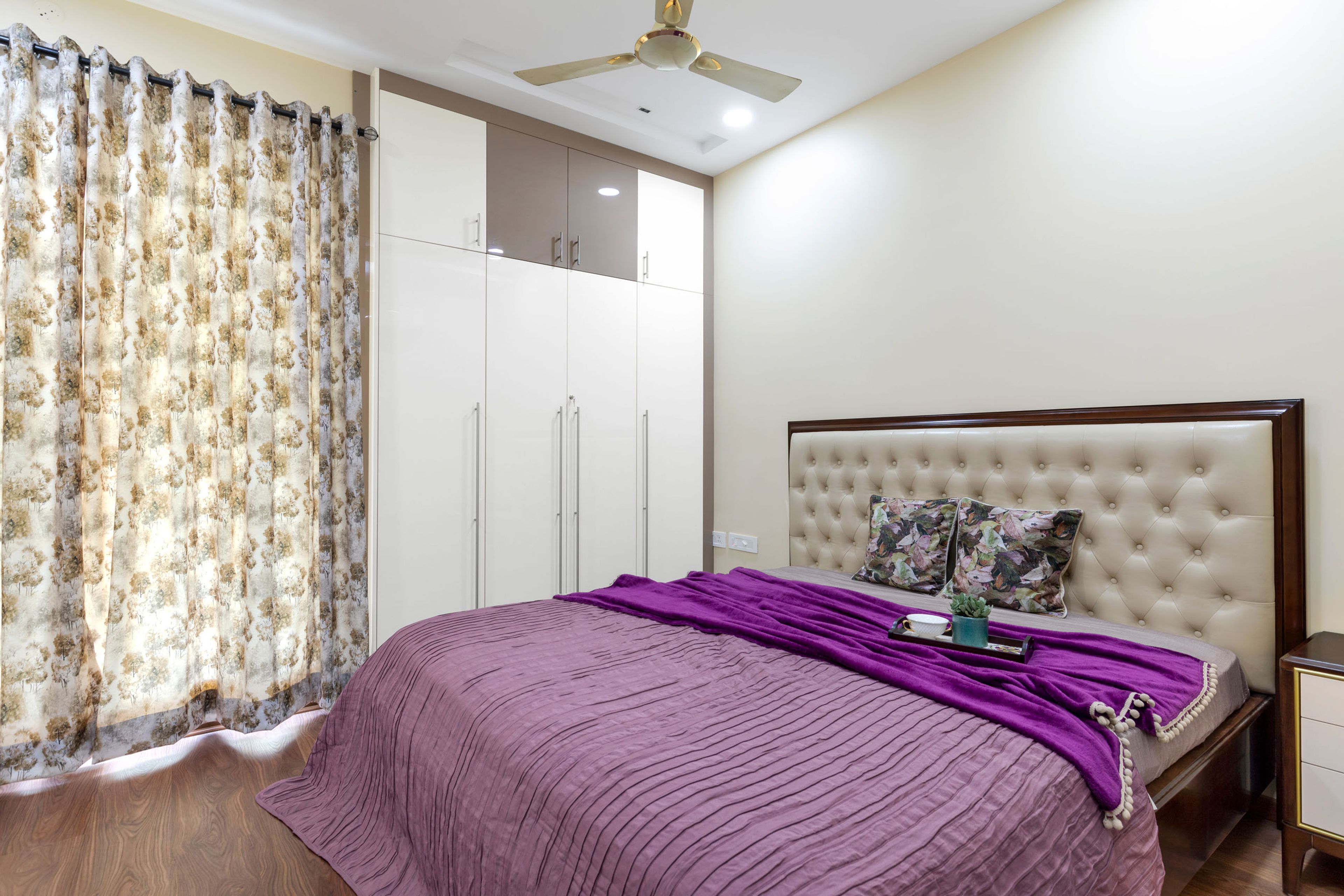 White Master Bedroom With Beige Tufted Headboard And 4-Door White Swing Wardrobe - Livspace