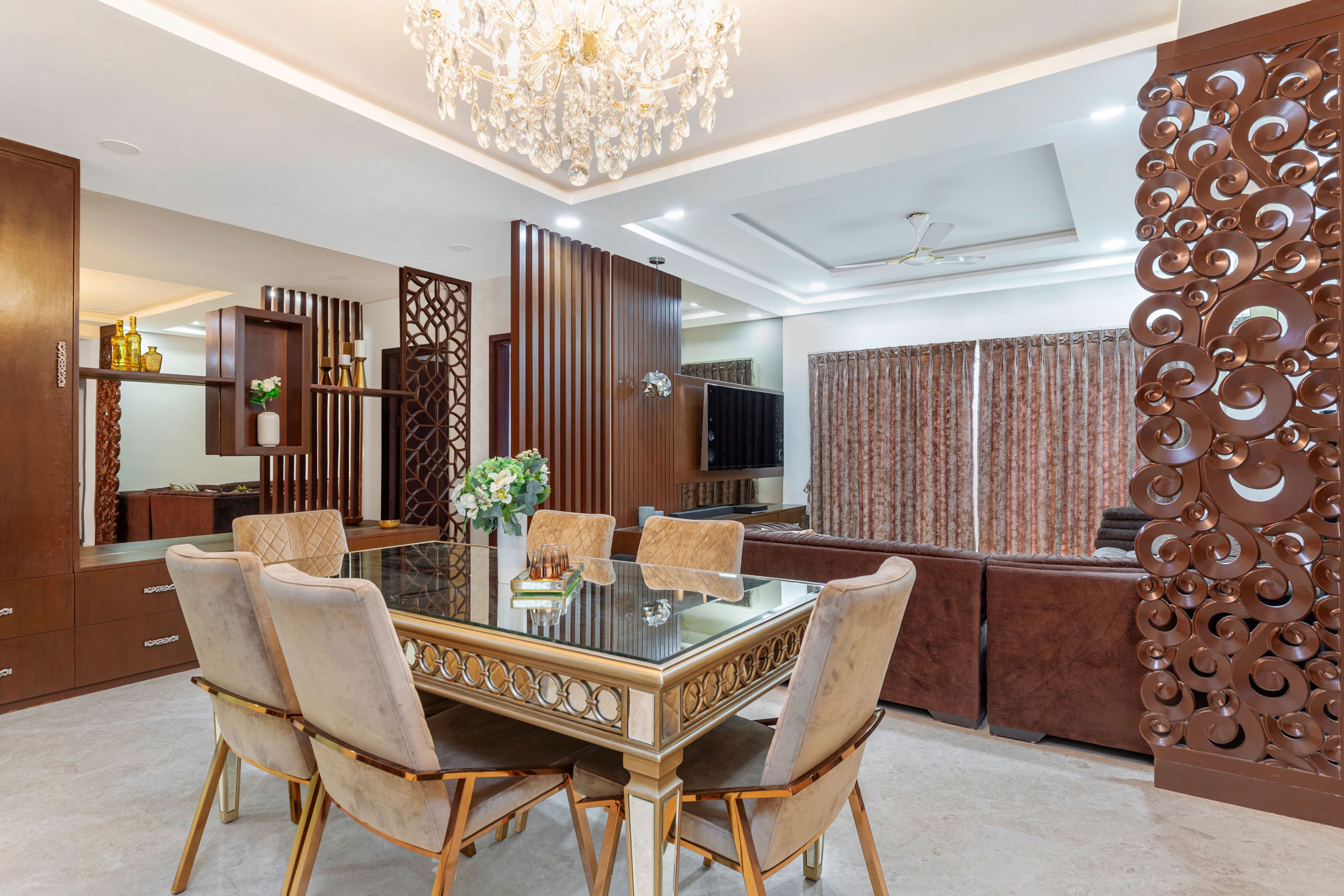 6-seater dining room design with beige tufted chairs and ornamental overhead chandelier - Livspace
