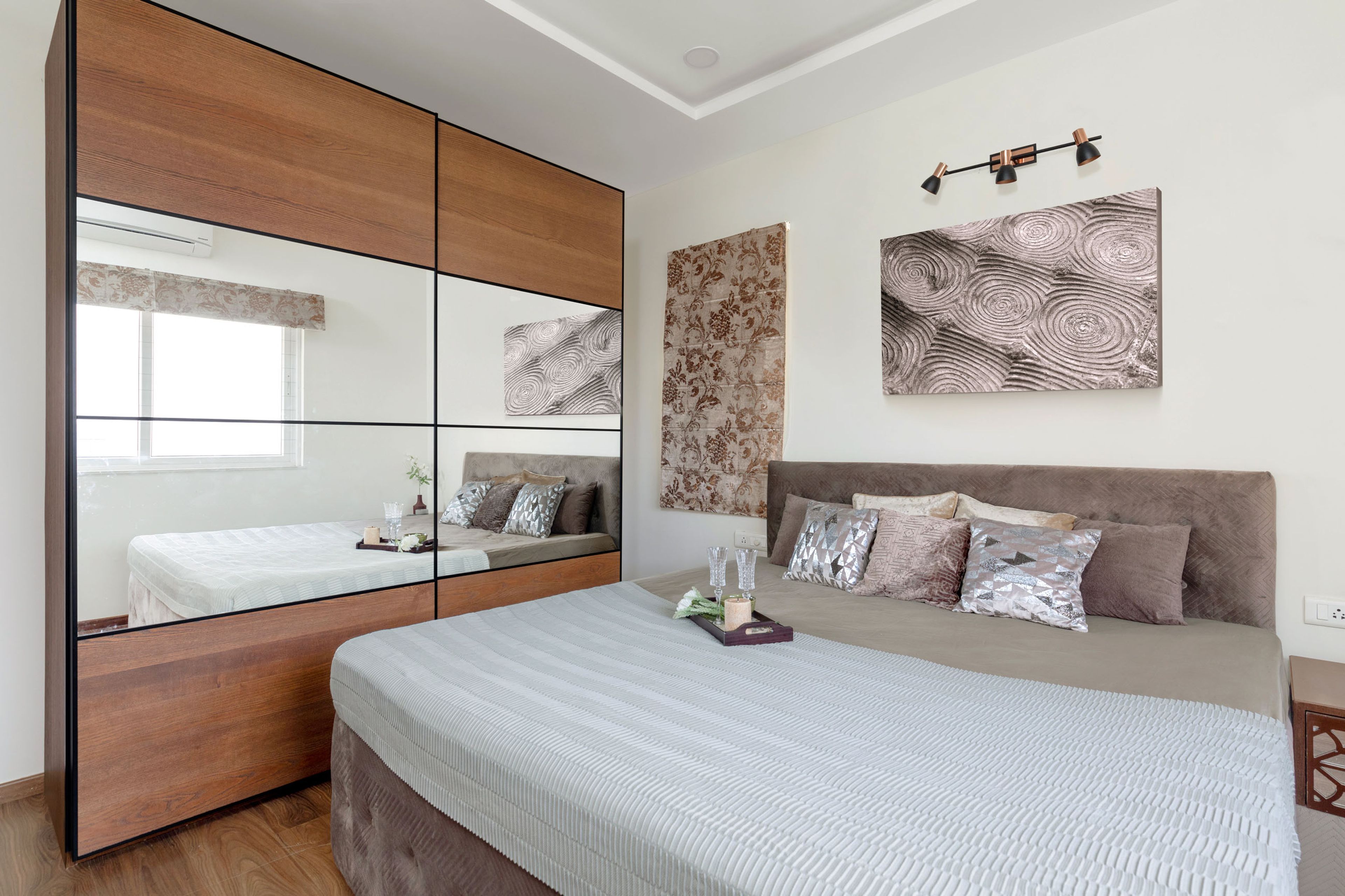 Guest bedroom with grey bed and 2-door wooden sliding wardrobe with mirrored panel - Livspace