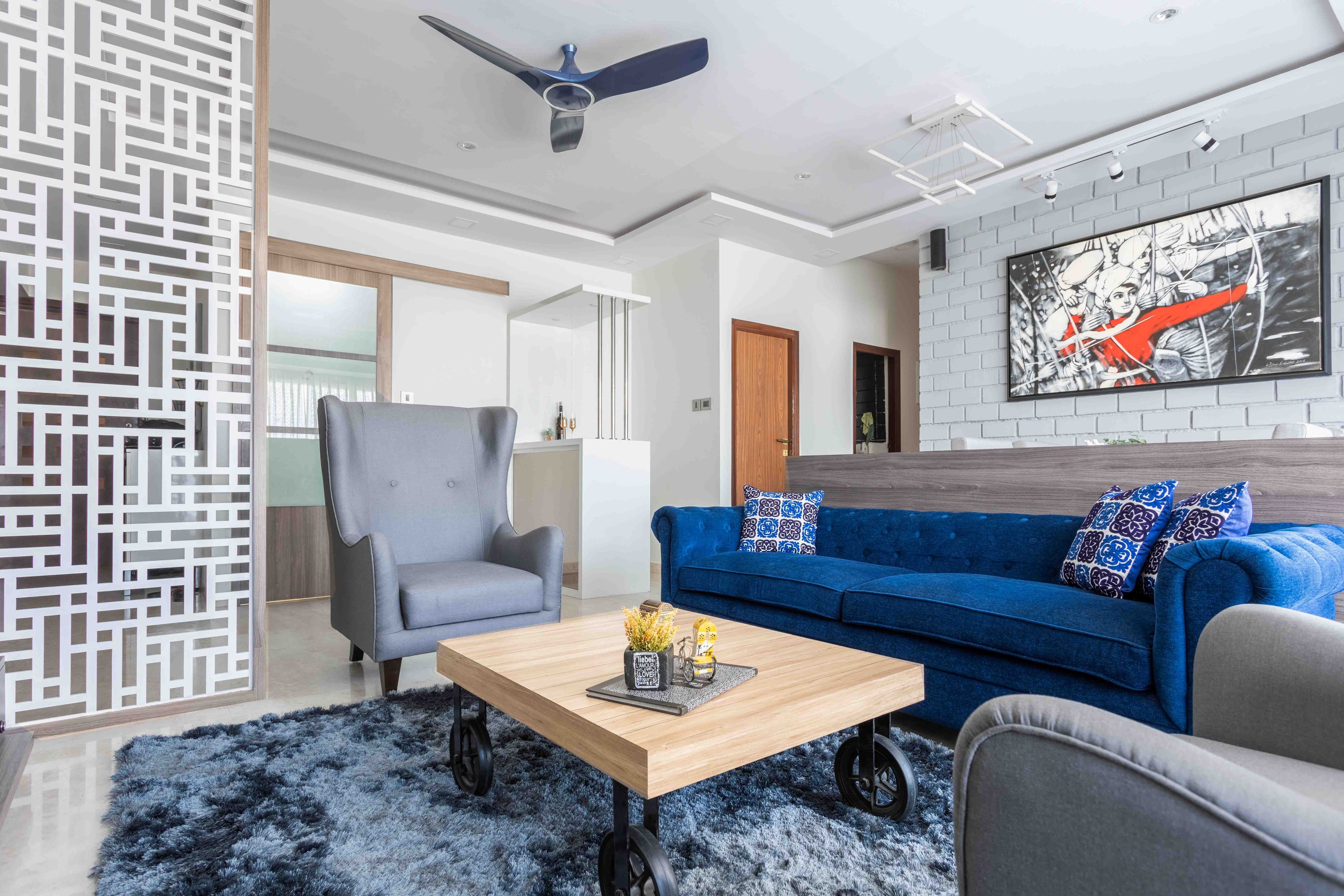 Blue And Grey Spacious Living Room Design With Wooden Coffee Table On Wheels And White Partition Wall - Livspace