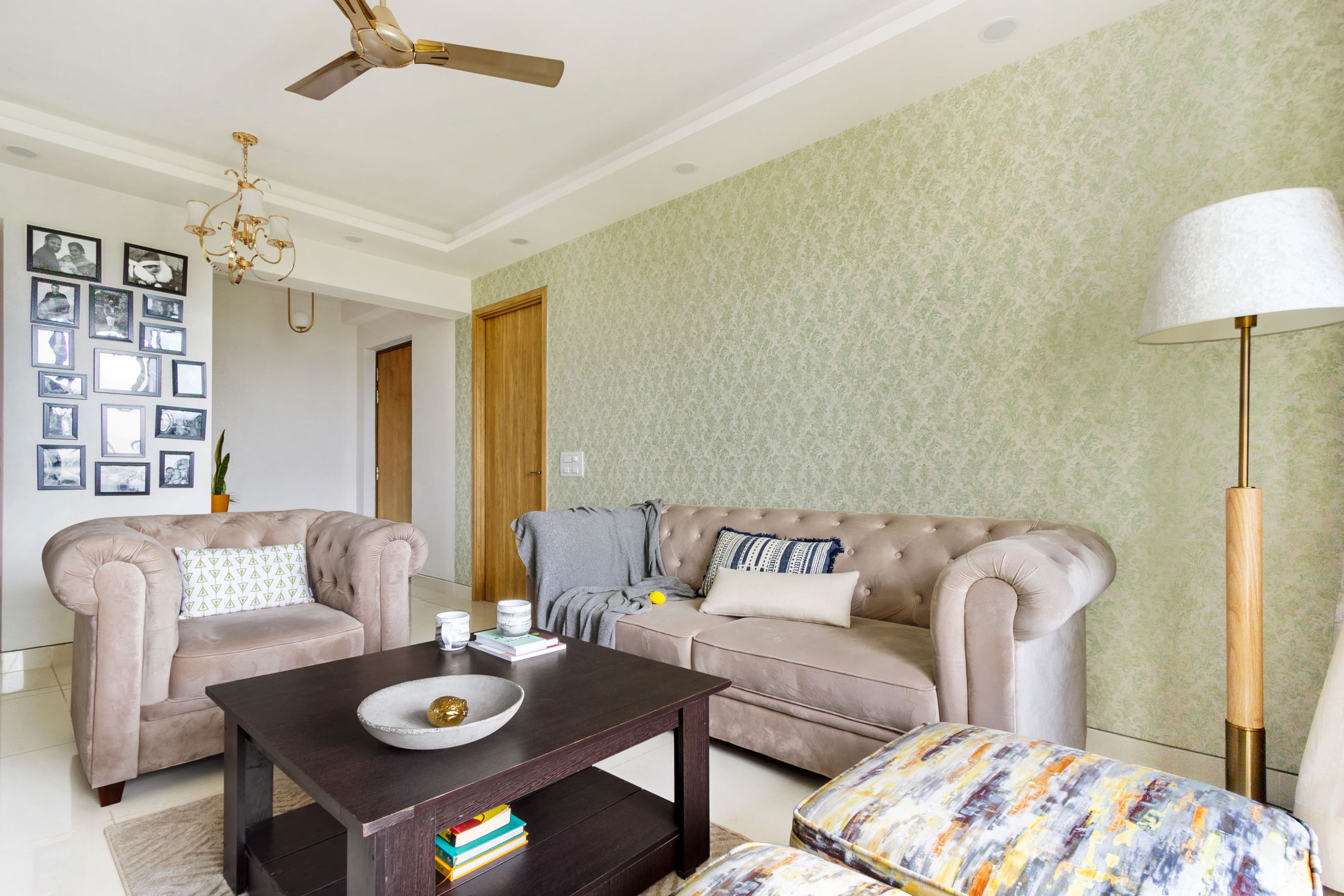 Spacious U-Shaped Living Room Design With Beige Sofa Set, Patterned Accent Chairs And Light Green Damask Wallpaper - Livspace