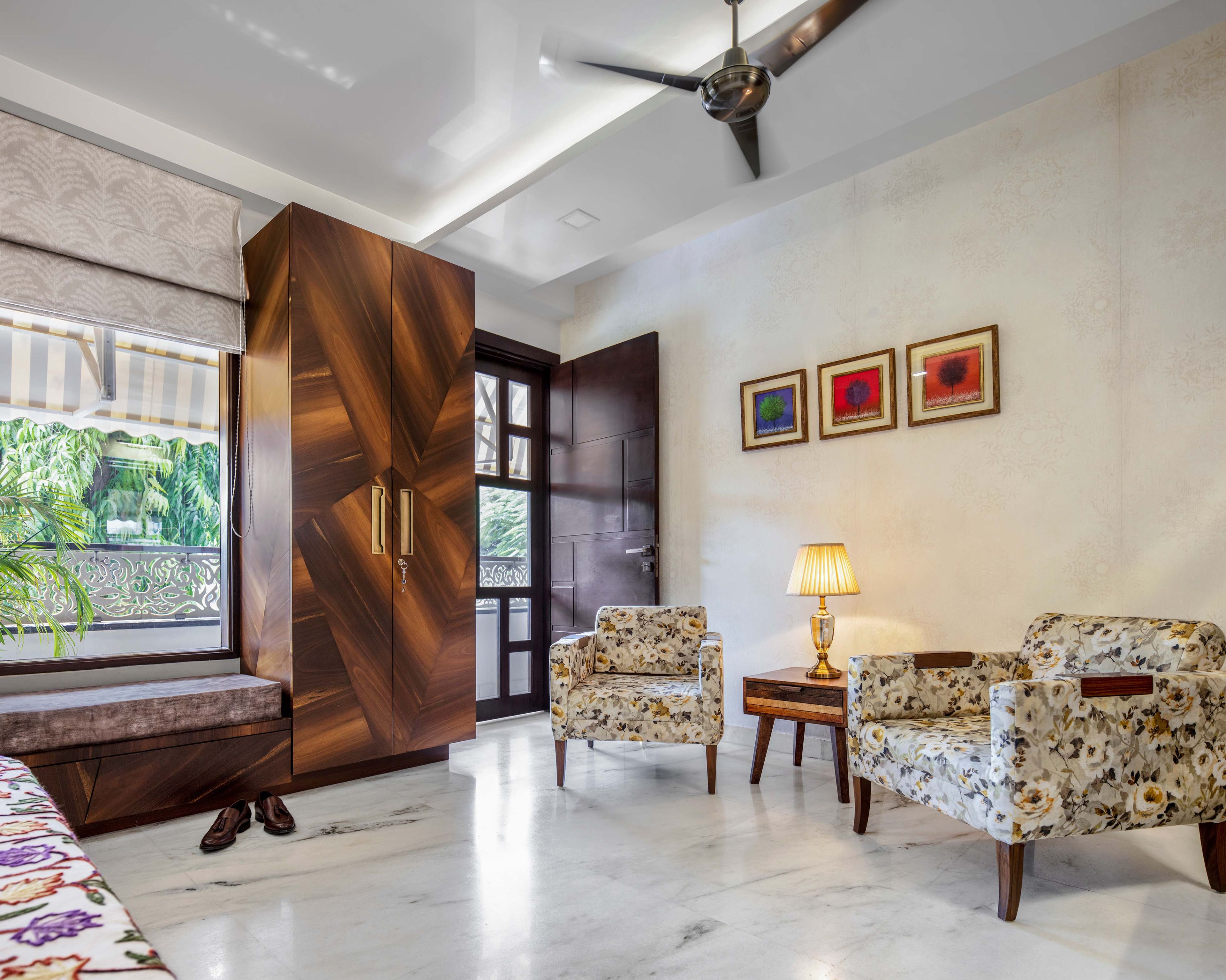 Master bedroom with patterned accent chairs and 2-door wooden swing wardrobe - Livspace