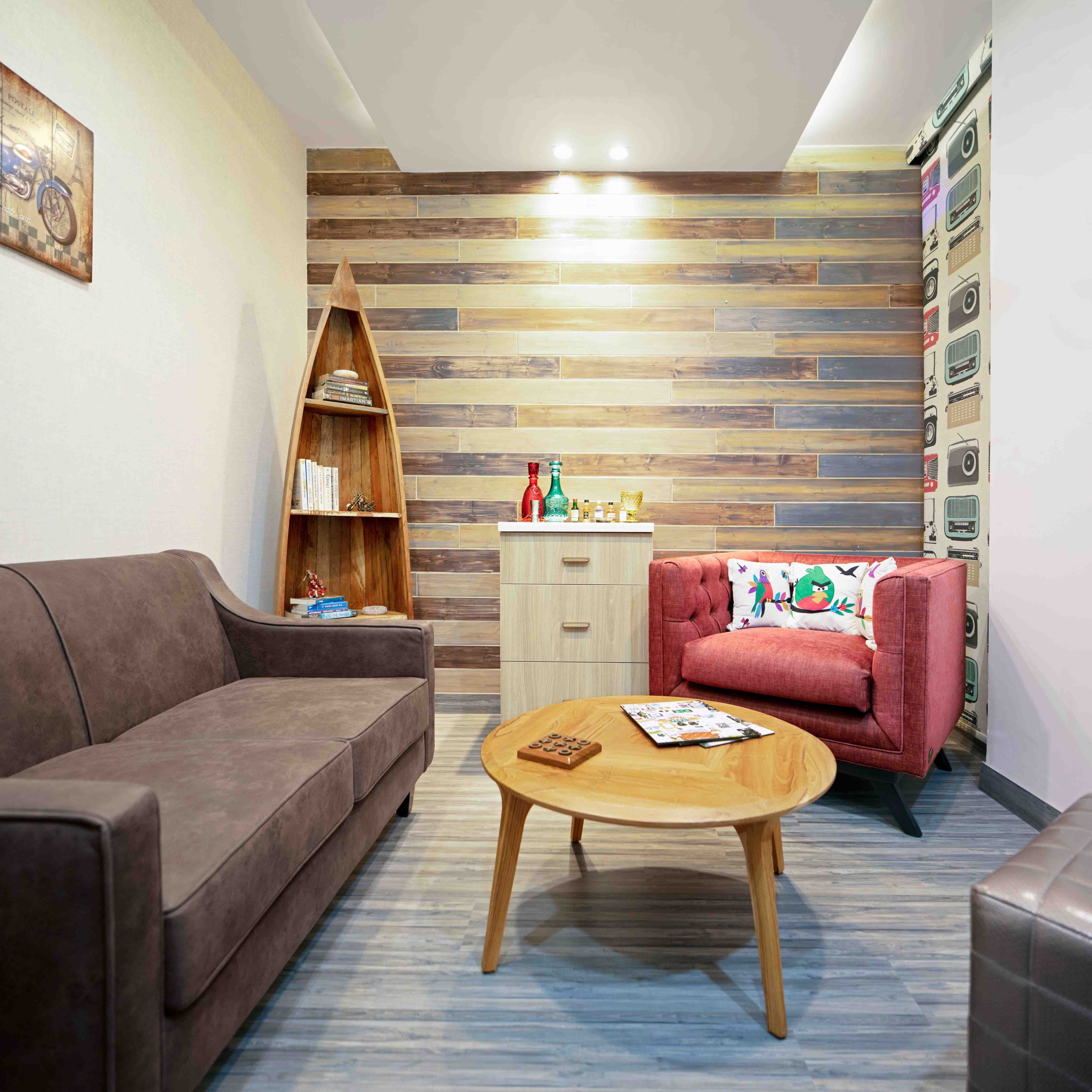 Family room with brown and red sofa, round wooden coffee table and wooden accent wall with subway pattern - Livspace
