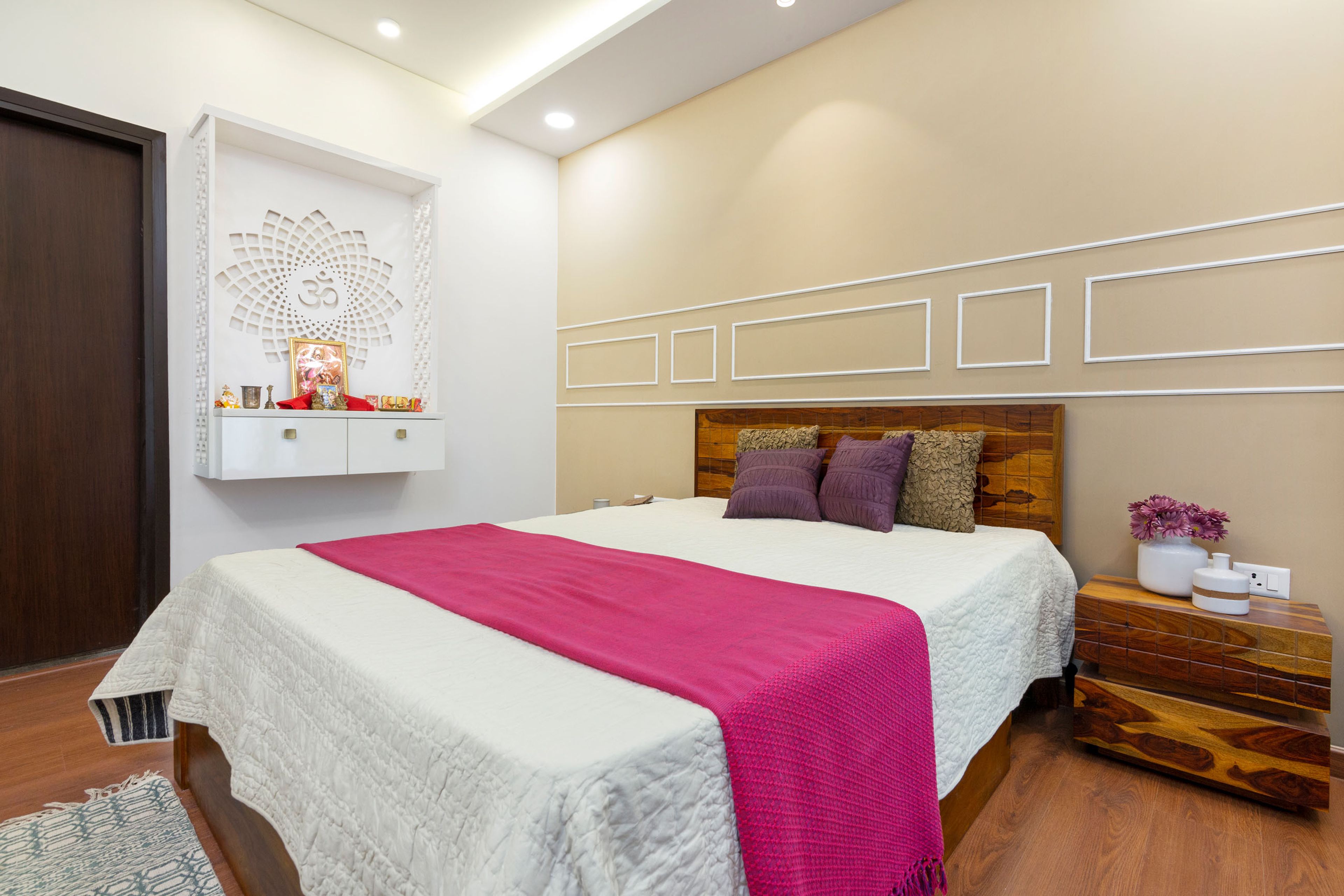Guest Bedroom With Beige Accent Wall And Wall Trims, Wall-Mounted White Mandir Unit And Wooden Side Table- Livspace